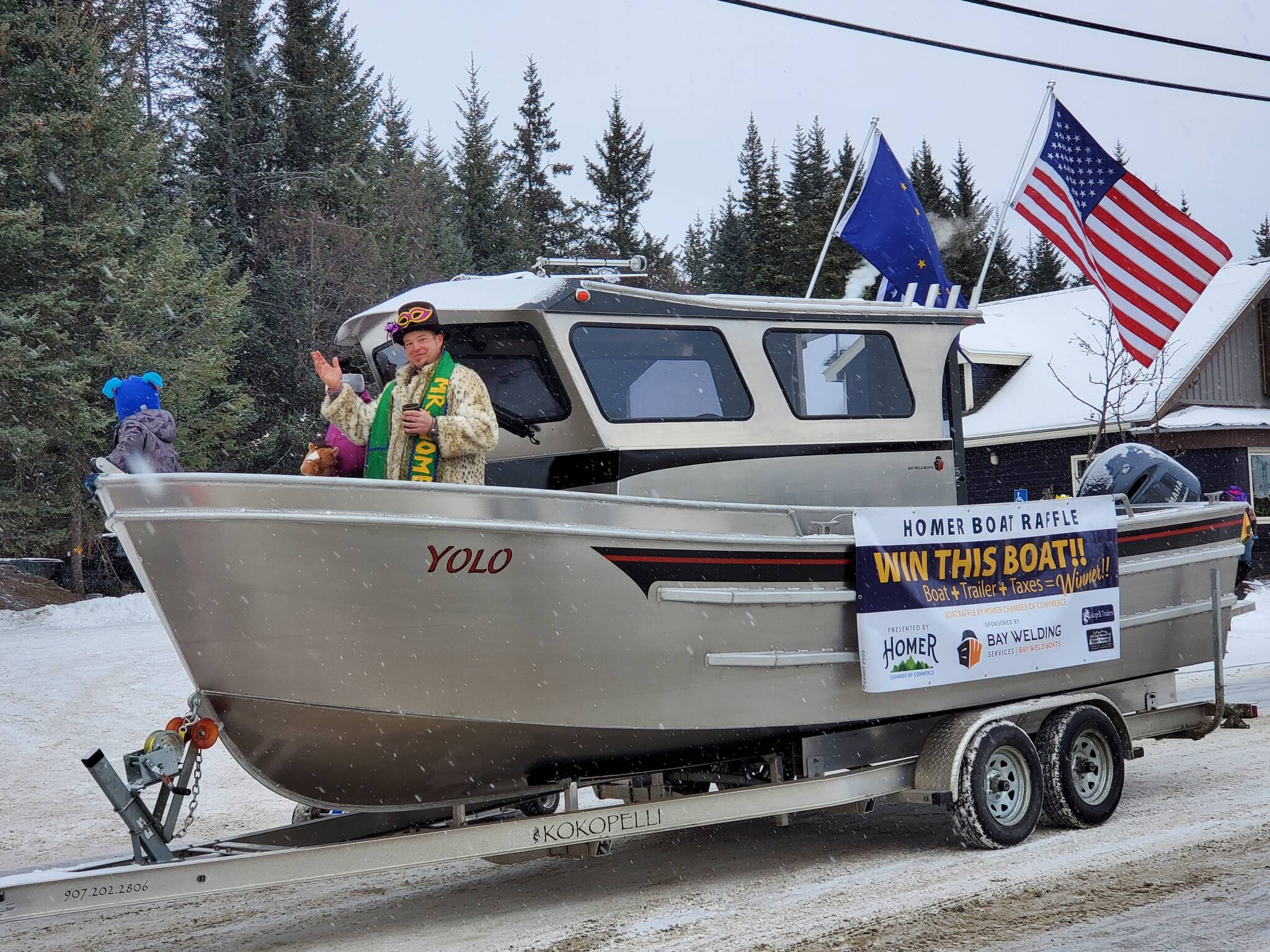 Garrett Brooks, winner of the 2023 Mr. Homer contest, waves to the crowd from a Bay Welding boat serving as the Homer Boat Raffle prize and the Homer Chamber of Commerce float in the 69th Annual Winter Carnival Parade on Saturday, Feb. 11, 2023 in Homer, Alaska. Photo by Delcenia Cosman