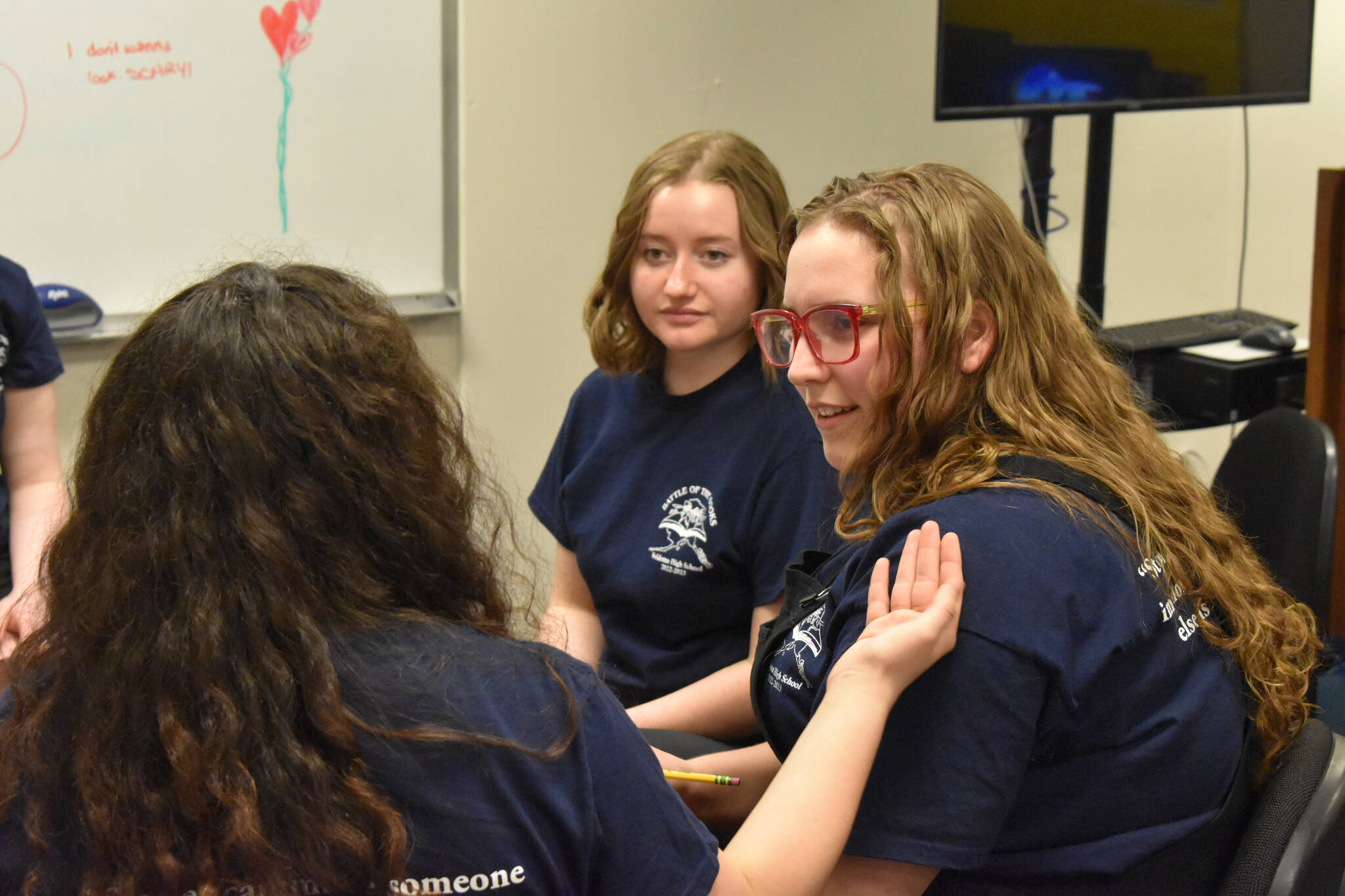 Lyndzi Gaucin describes her reasoning to her teammates, Leihla Harrison and Emma Knowles as they discuss their response to a question during Kenai Peninsula Borough School District High School Battle of the Books Final on Tuesday, Feb. 7, 2023 at Soldotna High School in Soldotna, Alaska. (Jake Dye/Peninsula Clarion)