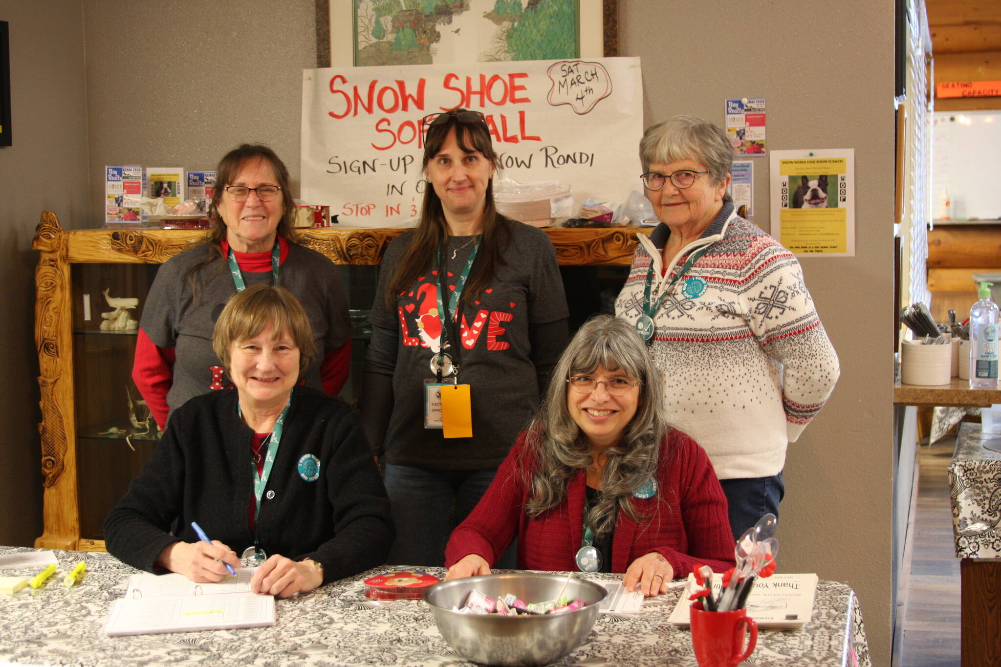 Back to front, from left to right: Poll workers Bobby Ness, Jennifer Dress, Carol Slavik, Mary Perry, and Loretta Stapel pose by the check-in table at the Anchor Point Senior Center during the special borough mayoral election on Tuesday, Feb. 14, 2023 in Anchor Point, Alaska. (Photo by Delcenia Cosman/Homer News)