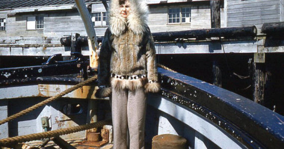 Posing stiffly in the bow of the M.S. Hygiene, along the Alaska coast, is Nurse Grace Heutink, clad in a warm fur parka. (Photo courtesy of the Fenger Family Collection)