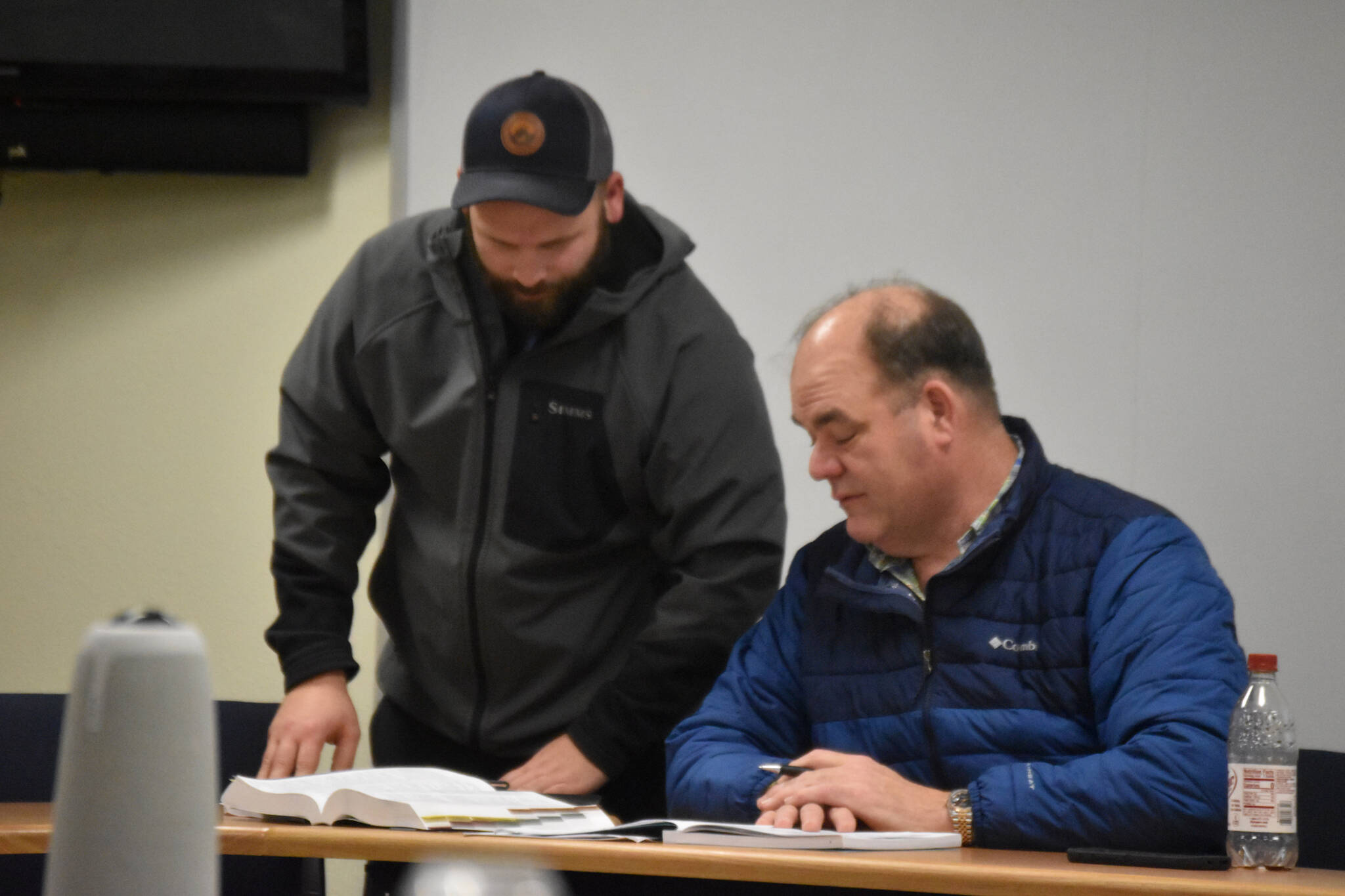 Alaska Department of Fish and Game Northern Kenai Peninsula Area Manager Colton Lipka shares information with Kenai/Soldotna Fish and Game Advisory Council Chair Mike Crawford as the advisory council deliberates their position on a proposal to the Board of Fish during a meeting at Cook Inlet Aquaculture in Kenai, Alaska on Thursday, Feb. 16, 2023. (Jake Dye/Peninsula Clarion)