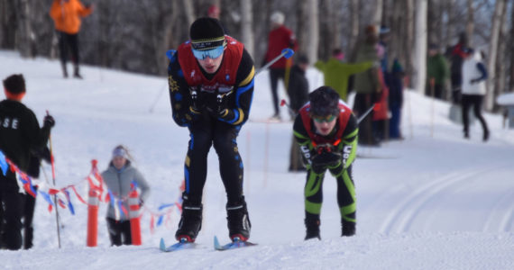 Garrett Briscoe, of Homer, tucks for a downhill, tightly pursued by Colony’s Clayton Steer during the boys 4x5-kilometer relay at the ASAA State Nordic Ski Championships at Kincaid Park in Anchorage, Alaska, on Saturday, Feb. 25, 2023. (Jake Dye/Peninsula Clarion)
