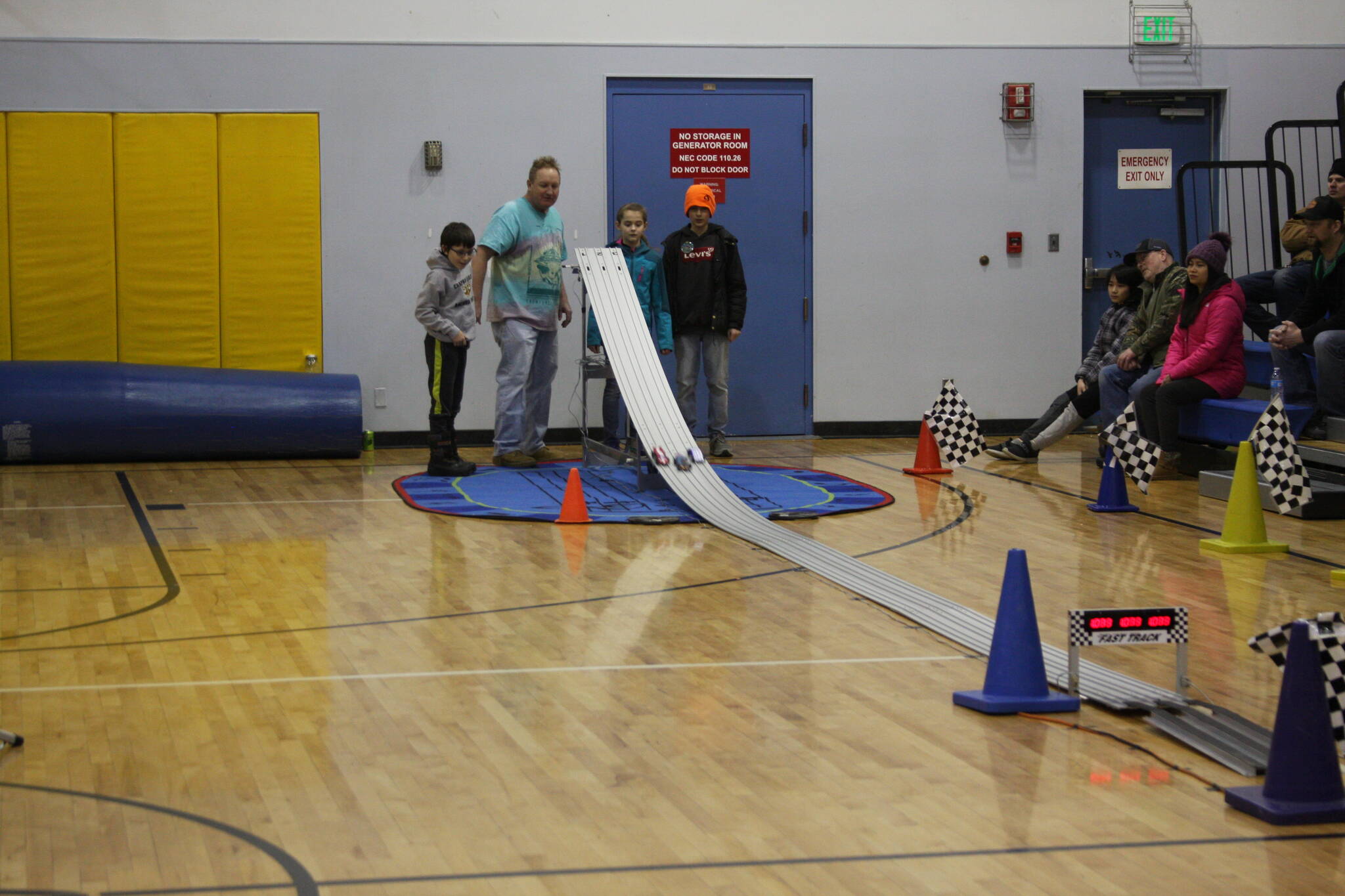 Pinewood derby contestants Simon Smith, Rox Shafer, and Jack Roderick and event volunteer Mike Smith watch the cars race down the track in the Chapman School gym on Saturday<ins>,</ins><ins> March 4</ins> in Anchor Point<ins>,</ins> <ins>Alaska</ins>. (Photo by Delcenia Cosman/Homer News)