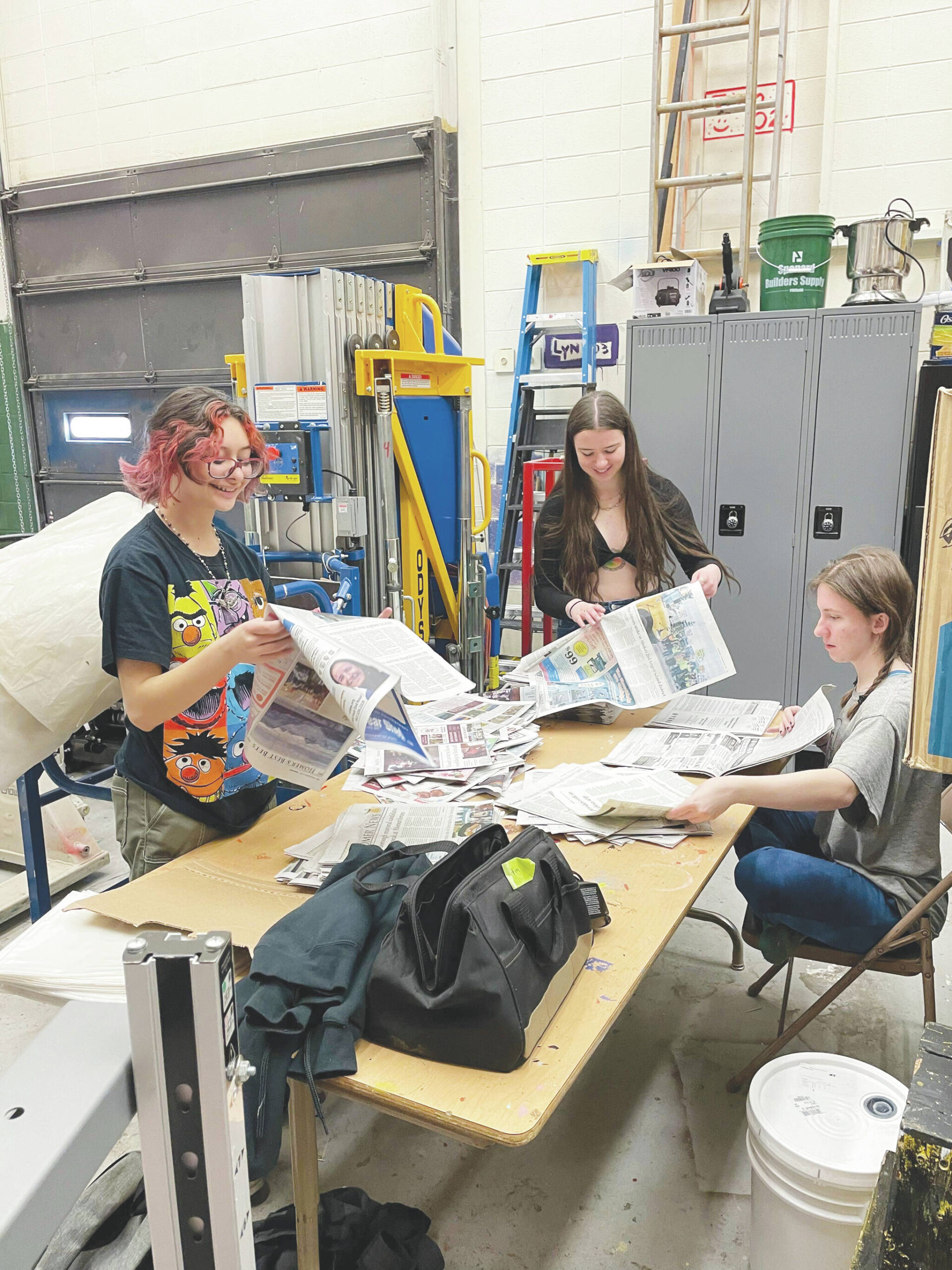 Photo by Emilie Springer/Homer News
Crew Vern Neveras, Bryce Glidden and Jasmine Lurus work in the Homer Mariner Theater shop on March 5, preparing newspaper props for the musical “Newsies.”