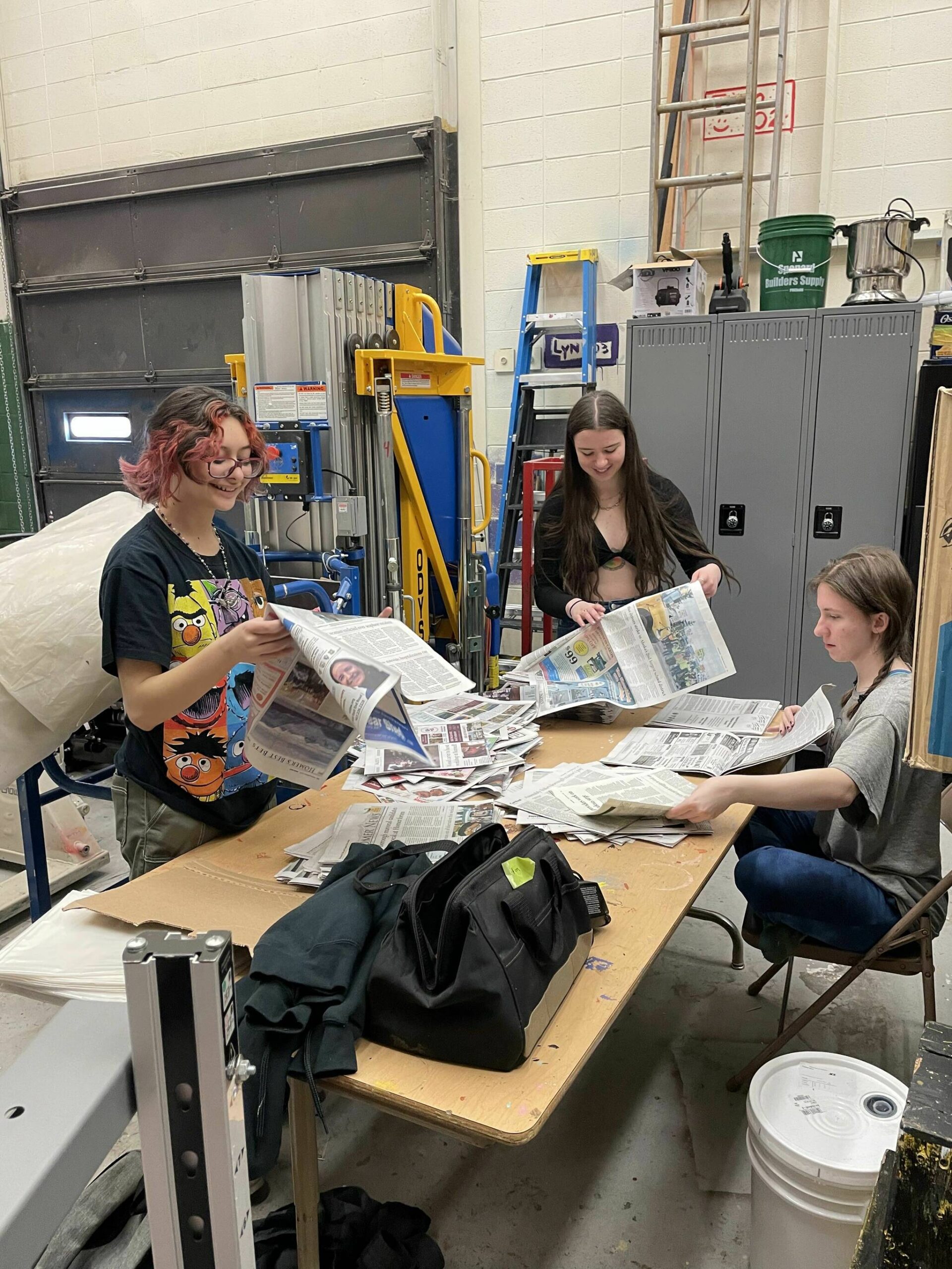 Newsies crew Vern Neveras, Bryce Glidden and Jasmine Lurus in the Homer Mariner Theater shop on March 5 preparing newspaper props for the musical.  Photo by Emilie Springer.