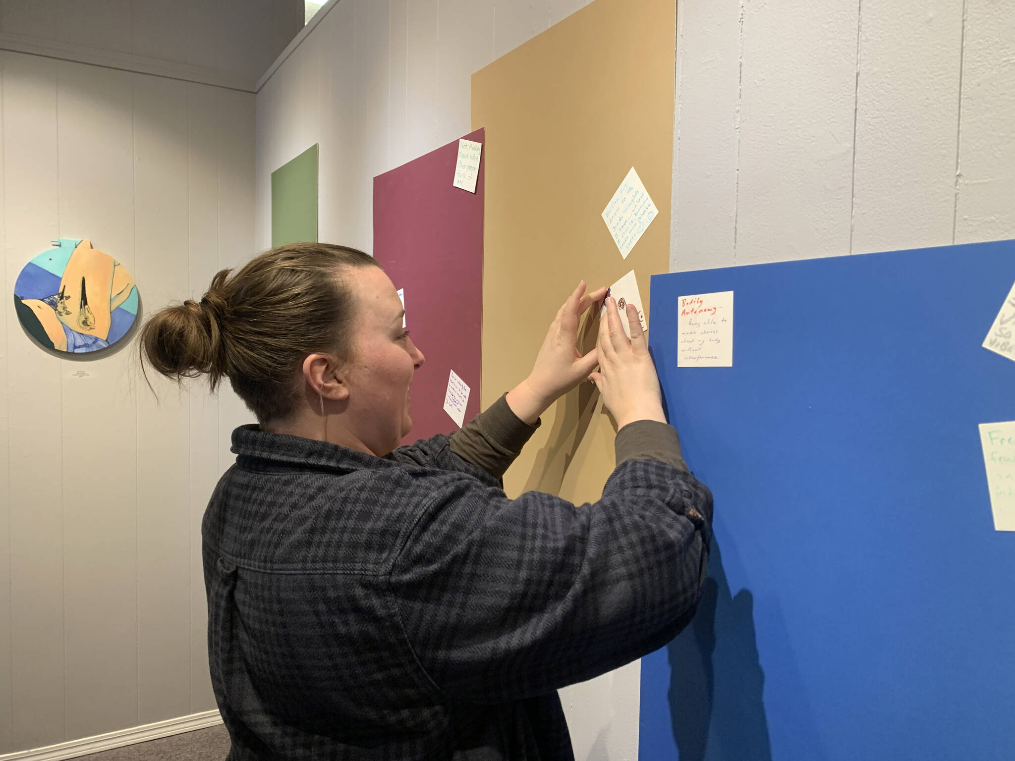 Tabitha Lindsay, visiting from Wisconsin, writes what bodily autonomy means to her during the exhibit at Homer Council on the Arts, March 16. (Photo by Christina Whiting/Homer News)