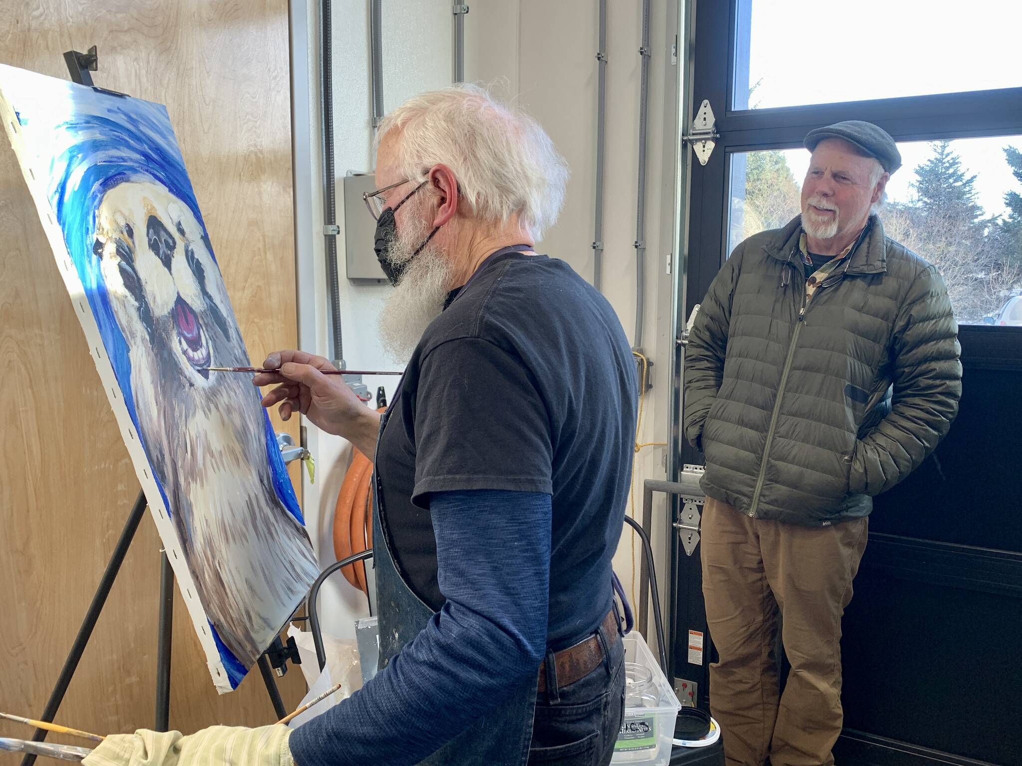 Potter Paul Dungan, right, looks on as Gary Lyons paints during the Ptarmigan Arts scholarship fundraiser at Grace Ridge Brewing on Saturday. (Photo by Christina Whiting/Homer News)
