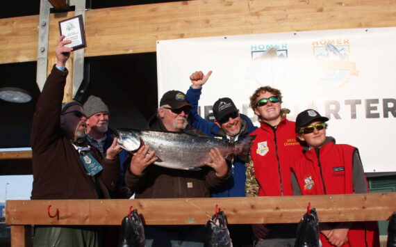 Photo by Delcenia Cosman / Homer News 
Tournament champion Gail Bilyeu, center, holds the winning fish during the Homer Winter King Salmon Tournament awards ceremony on Saturday. Pictured right are the tournament’s previous two champions, Weston and Andrew Marley.