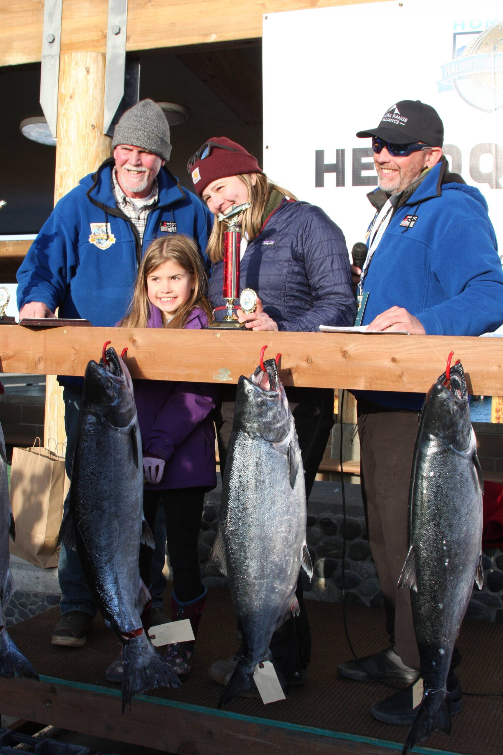 Second place winner Alivia Erickson (center) poses with her trophy during the Homer Winter King Salmon Tournament awards ceremony on Saturday. Photo by Delcenia Cosman