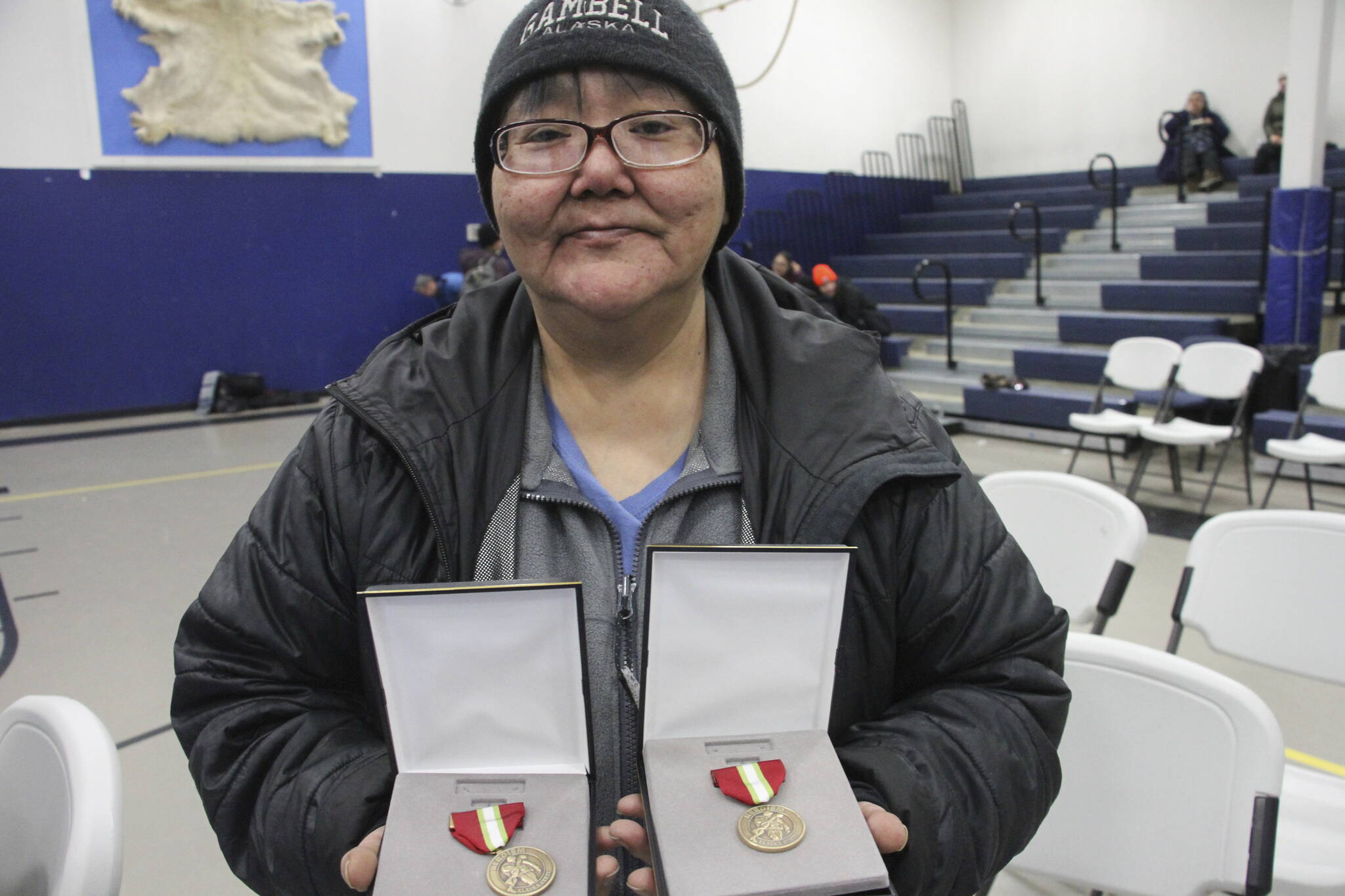 This March 28, 2023, photo shows JoAnn Kulukhon posing with two Alaska Heroism Medals presented posthumously to her uncles, Pvts. Luke and Leroy Kulukhon, during a ceremony in Gambell, Alaska. Sixteen Alaska National Guard members were honored for helping rescue the 11 crewmembers of a Navy plane that was shot down in 1955 by Soviet jet fighters and crash-landed about 8 miles from Gambell, on St. Lawrence Island, and 15 medals were presented posthumously. (AP Photo/Mark Thiessen)