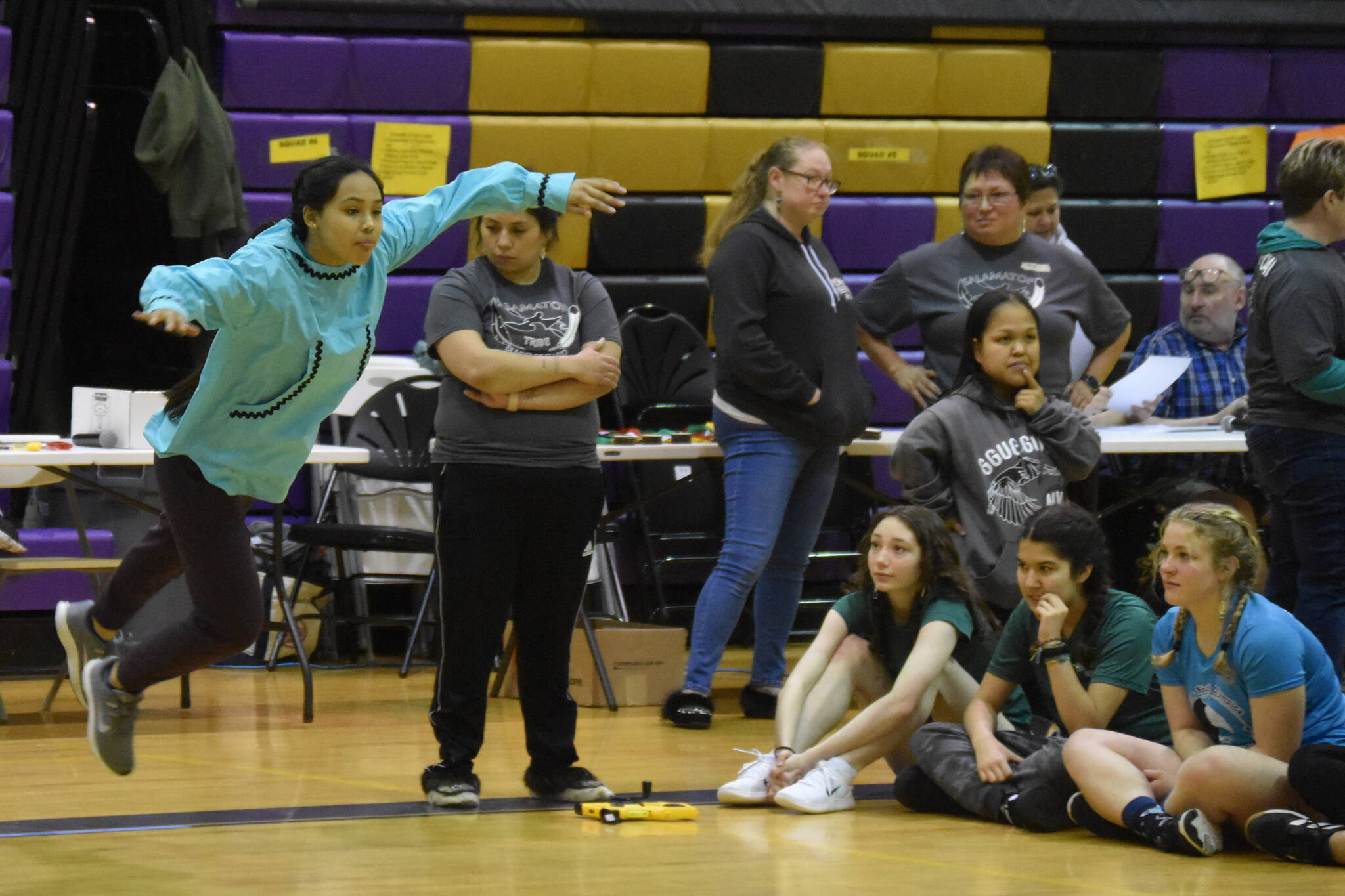 An athlete competing with the Salamatof Tribe leaps forward as she performs the Scissor Broad Jump during the Salamatof Tribe Traditional Native Games Invitational at Kenai Middle School in Kenai, Alaska, on Friday, April 14, 2023. (Jake Dye/Peninsula Clarion)