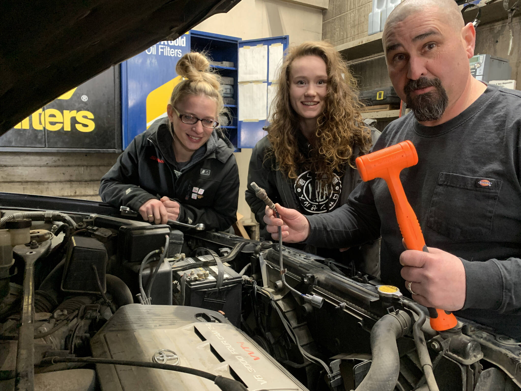 Melissa Sheldon, Tezlyn Kerrone and Robert Tarnoswki, owner of Sunny’s Service, pose in front of a car they were working on, March 2023.
