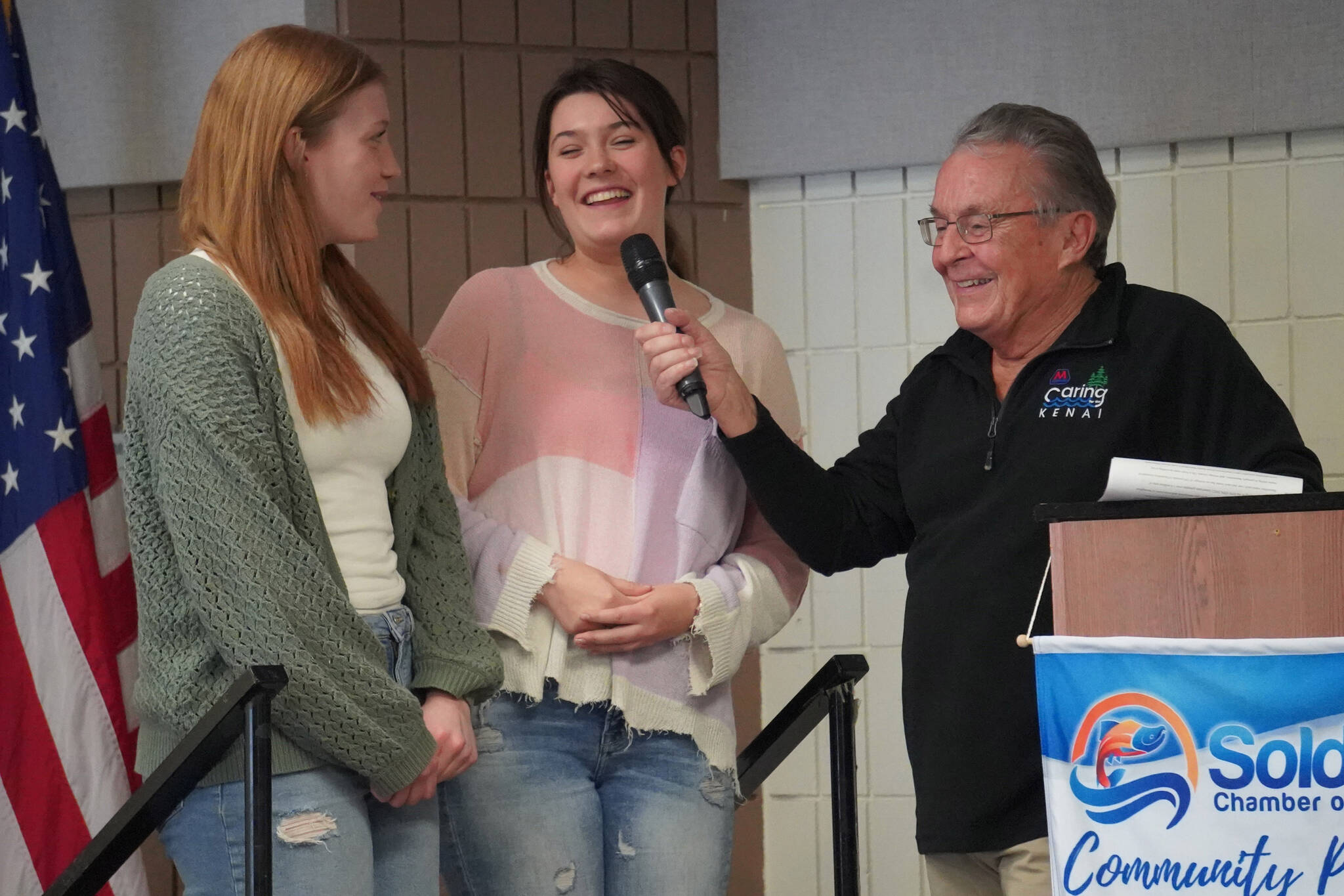 Hope Hillyer and Grace Henry, of Cook Inlet Academy, are introduced by Merrill Sikorski at the Caring for the Kenai Awards Celebration held during a Joint Chamber Luncheon on Wednesday, May 3, 2023, at the Soldotna Regional Sports Complex in Soldotna, Alaska. (Jake Dye/Peninsula Clarion)