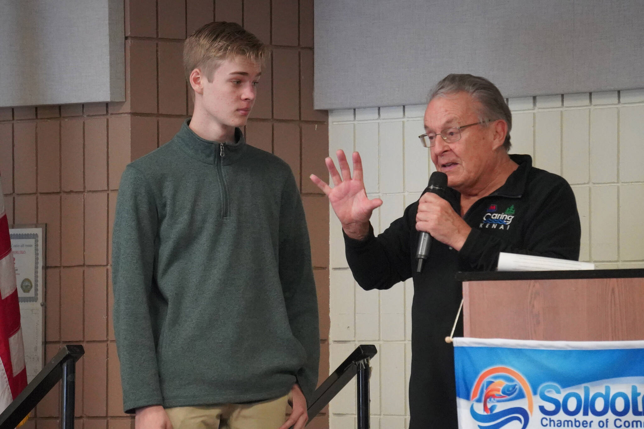 First Place Winner Paxton McKnight, of Cook Inlet Academy, is introduced by Merrill Sikorski at the Caring for the Kenai Awards Celebration held during a Joint Chamber Luncheon on Wednesday, May 3, 2023, at the Soldotna Regional Sports Complex in Soldotna, Alaska. (Jake Dye/Peninsula Clarion)