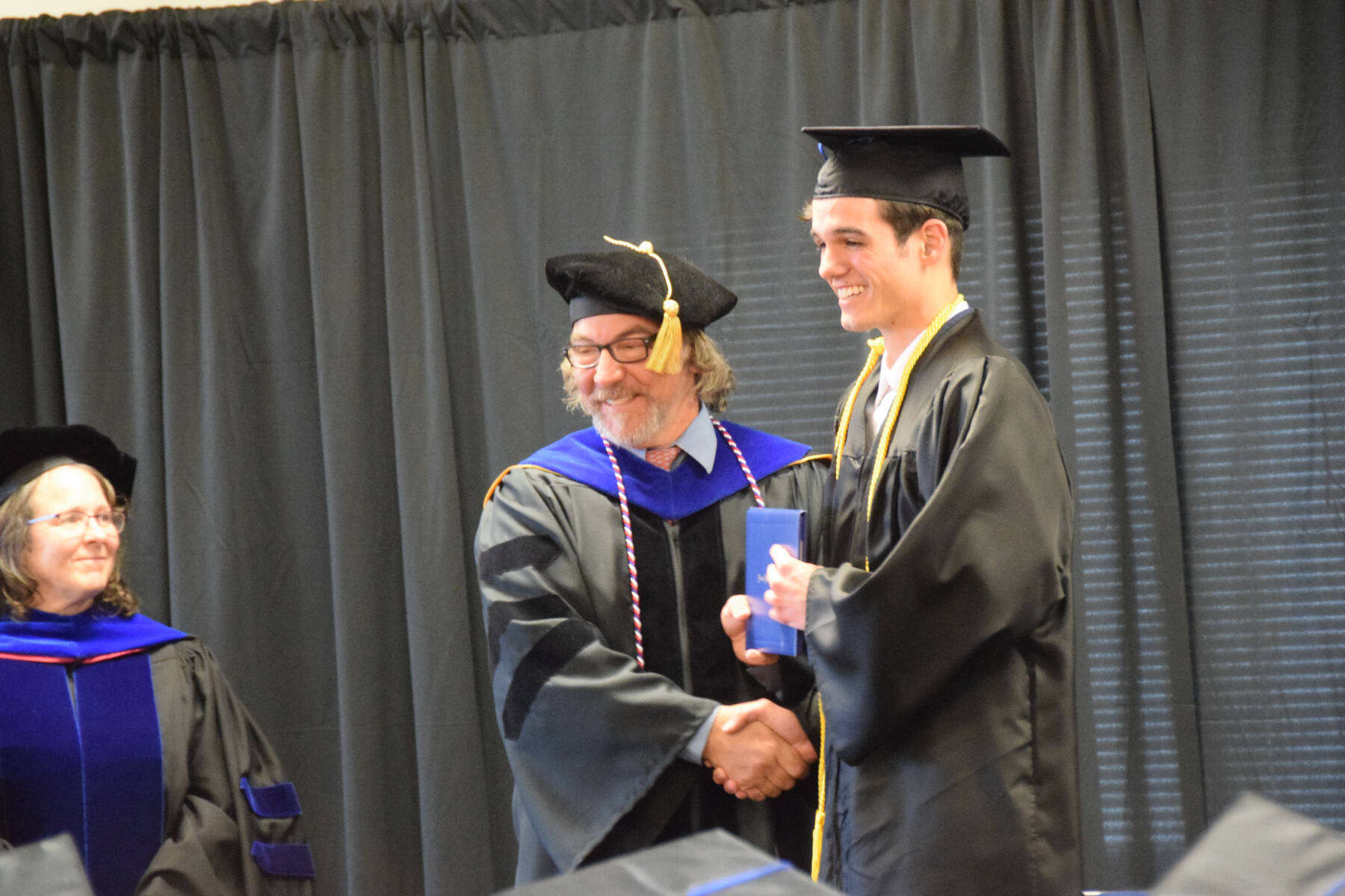 Kachemak Bay Campus director Dr. Reid Brewer (center) presents Jonathan Rozeboom (right) with his Associate of Arts diploma during the 2023 KBC Commencement on Wednesday, May 10, 2023 in Homer, Alaska. (Photo by Delcenia Cosman/Homer News)