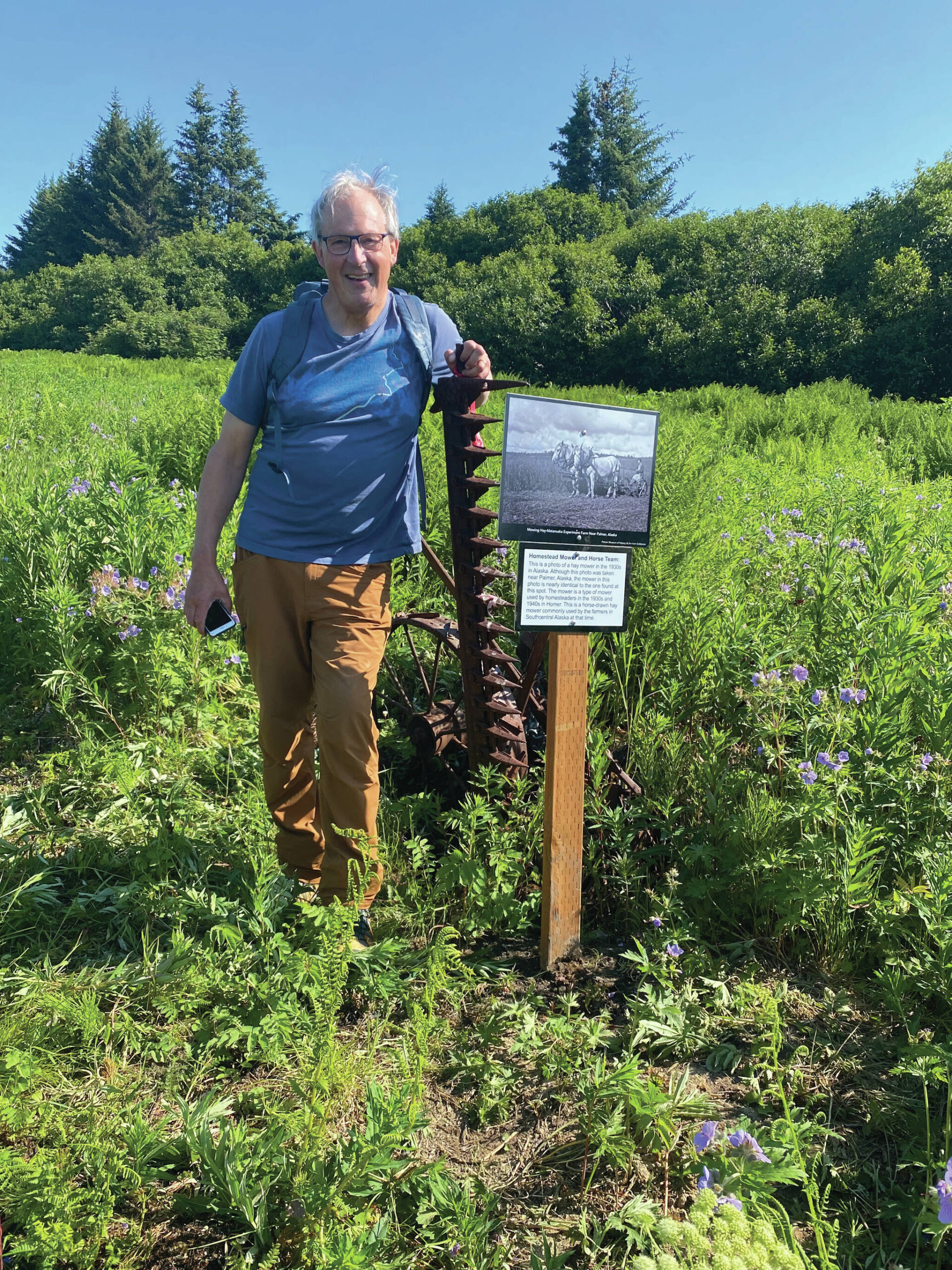 HTA volunteer Charlie Barnwell installing plaque of rake mower artifact from Homesteader days, Homestead Trail, June 2022. (Photo provided by HTA)