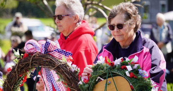 Attendees affix poppies to wreaths during a Memorial Day ceremony on Monday, May 29, 2023, at Leif Hanson Memorial Park in Kenai, Alaska. (Jake Dye/Peninsula Clarion)