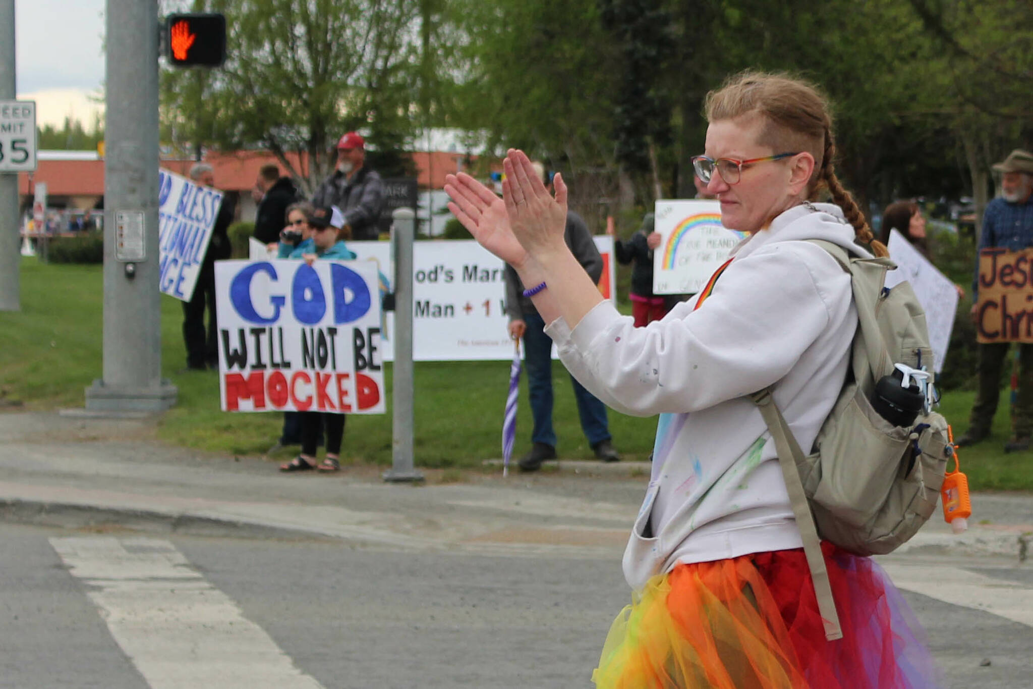 Leslie Byrd welcomes marchers to Soldotna Creek Park as part of Soldotna Pride in the Park while protesters stand in the background on Saturday, June 3, 2023 in Soldotna, Alaska. (Ashlyn O’Hara/Peninsula Clarion)