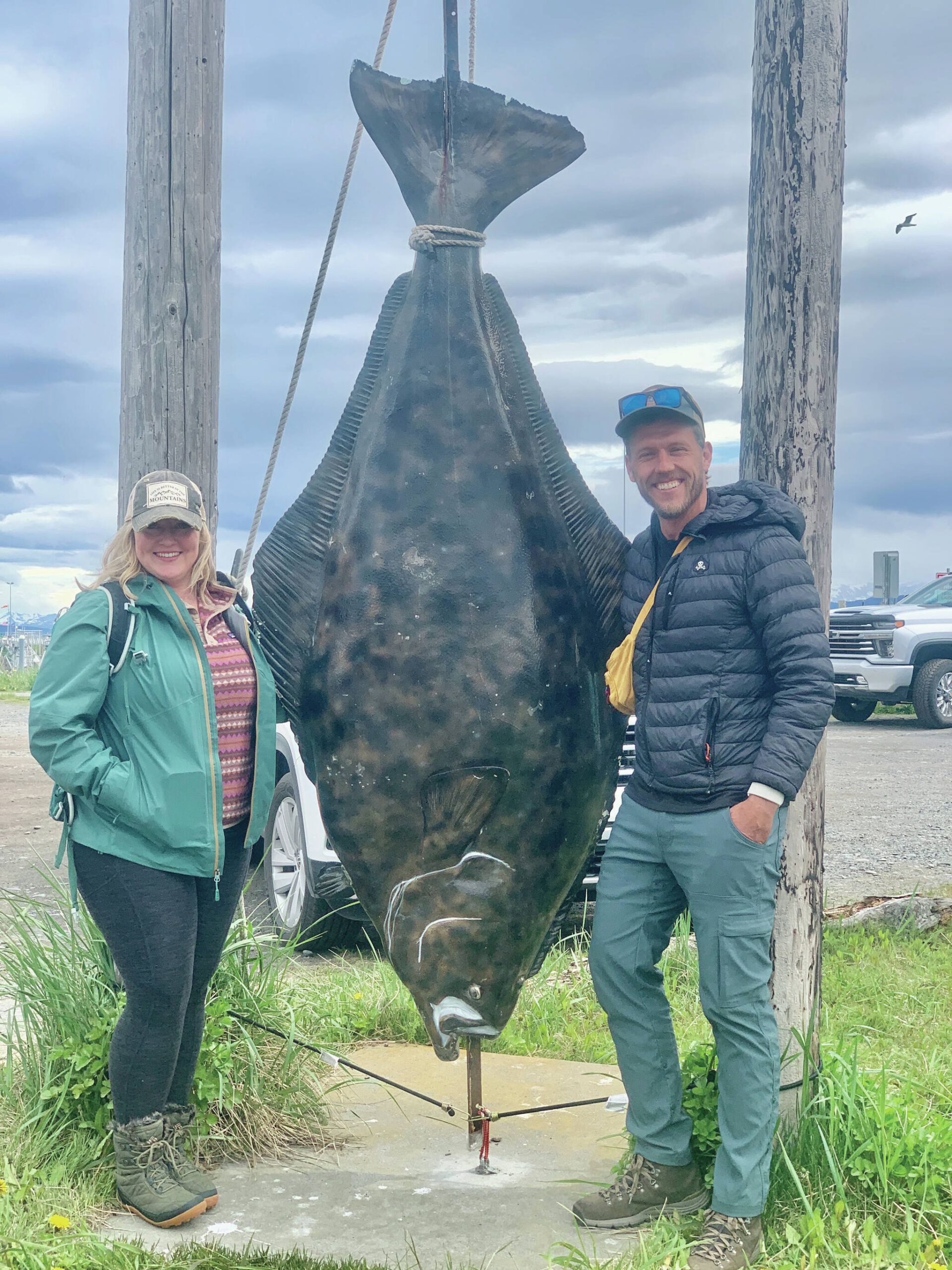 Singer-songwriters Barbara Sim from South Carolina and Brandon Mills from Nashville, Tennesee, pose alongside Hal, a fiberglass halibut at the Chamber’s Spit visitor center, June 8. (Photo by Christina Whiting/Homer News)