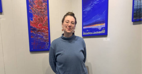 Homer artist Jenna Gerrety poses with two of the paintings in her exhibit, "Omnipresence: A Blue Period," on display at Homer Council on the Arts through June. Photo provided by Jenna Gerrety