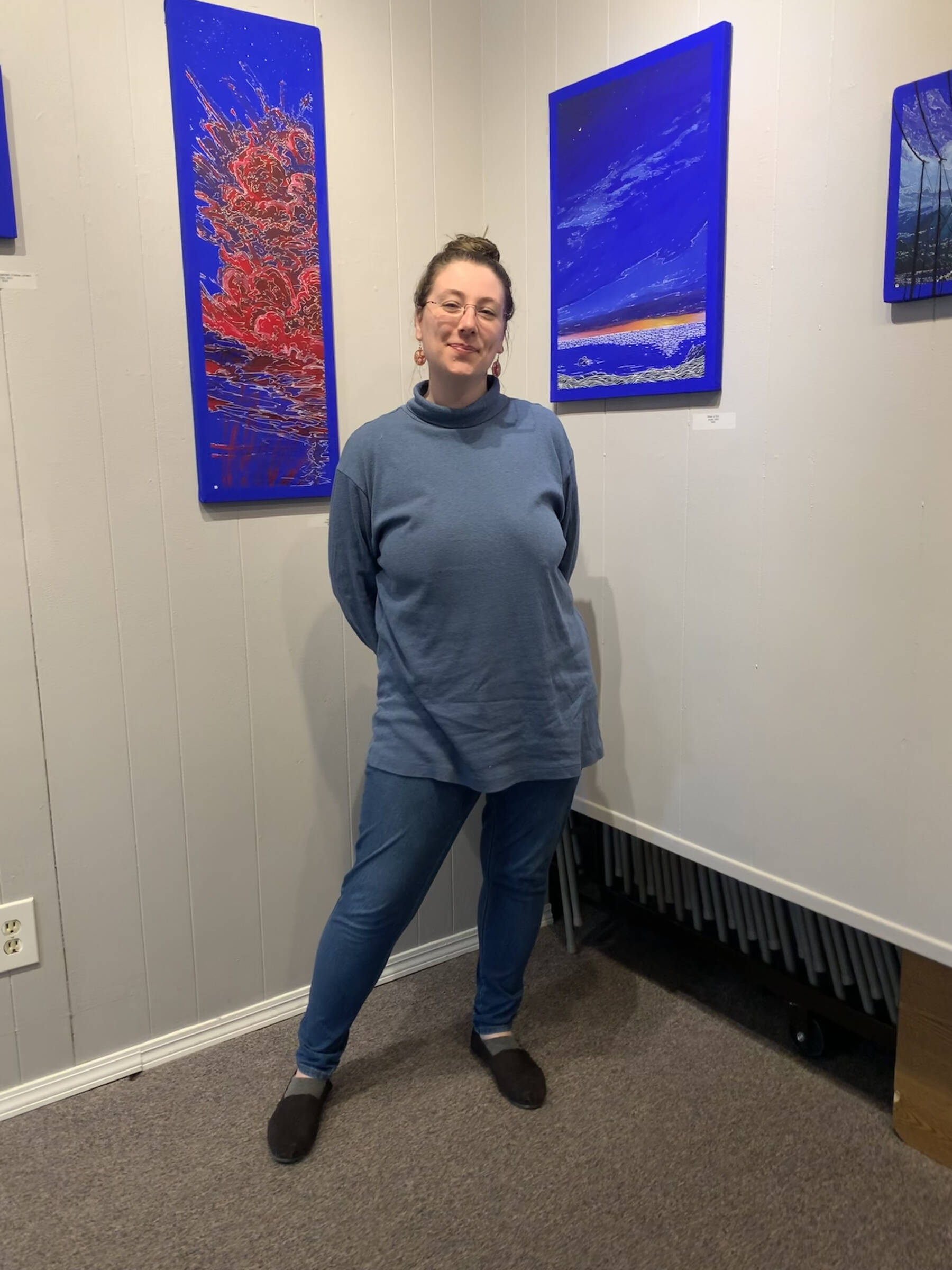 Homer artist Jenna Gerrety poses with two of the paintings in her exhibit, “Omnipresence: A Blue Period,” on display at Homer Council on the Arts through June. Photo provided by Jenna Gerrety