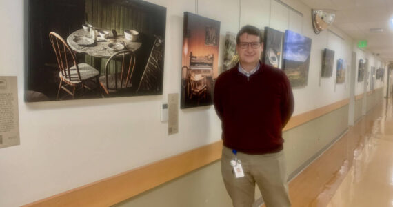 Dr. Edson Knapp is pictured n June 22, 2023 with his photography exhibit, "Joy in the Journey," on display at South Peninsula Hospital's gallery through July 4. Photo by Christina Whiting