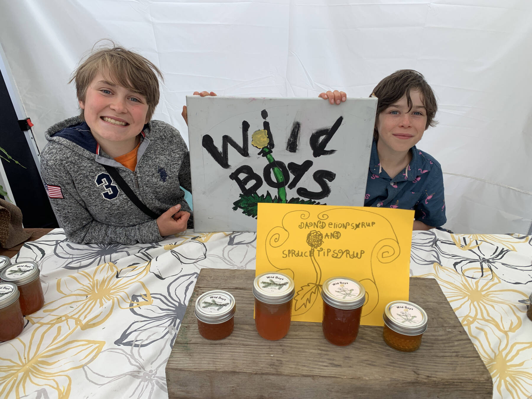 Wild Boys, brothers Graysen Oyster, 11 (left), and Rylan Oyster, 9, sell their homemade dandelion and spruce tip products at the Homer Farmers Market on Wednesday, June 28, 2023 in Homer, Alaska. Photo by Christina Whiting