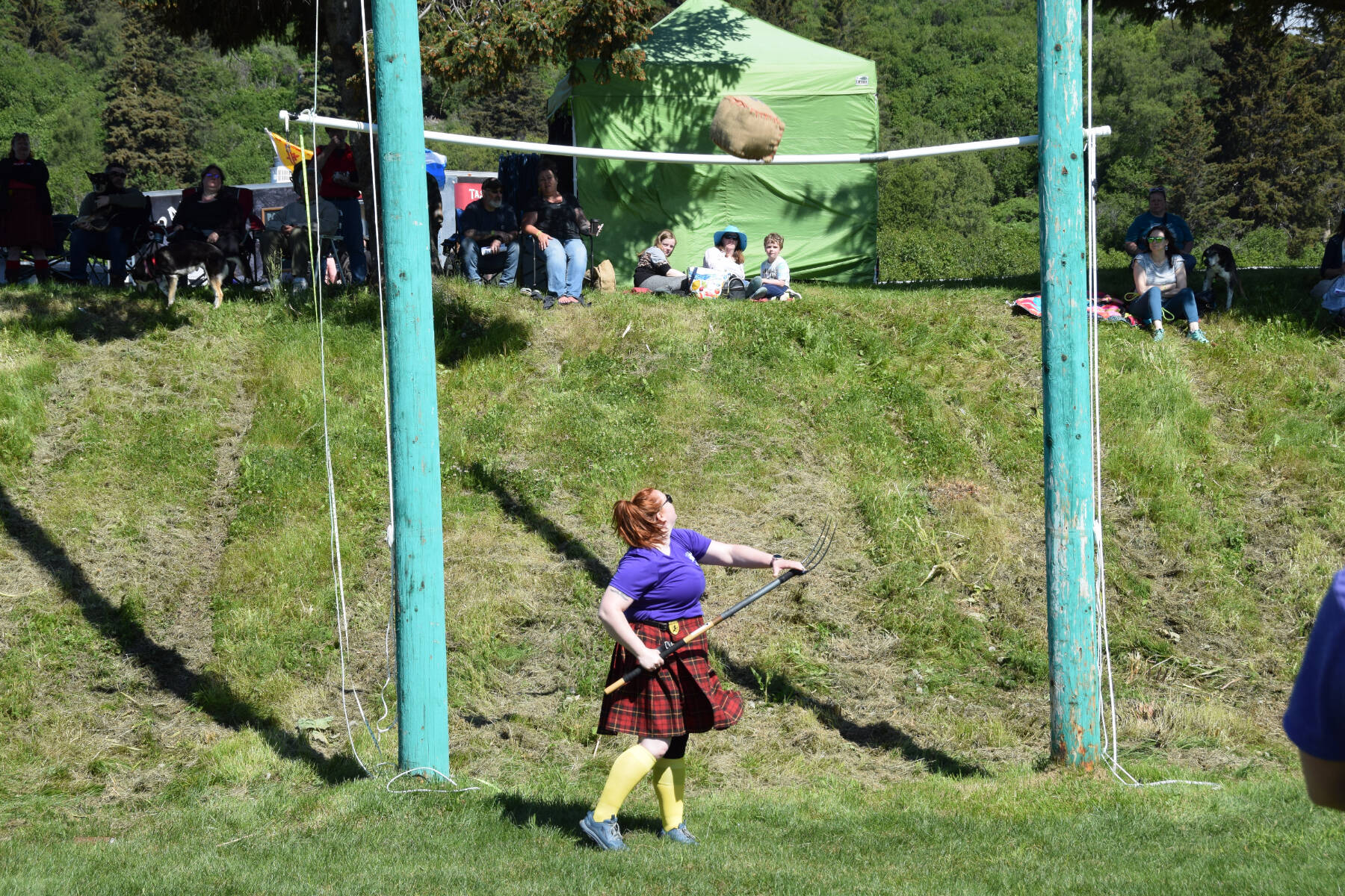 A Kachemak Bay Highland Games participant uses a pitchfork to toss a sheaf over the crossbar on Saturday, July 1, 2023 at Karen Hornaday Park in Homer, Alaska. (Delcenia Cosman/Homer News)