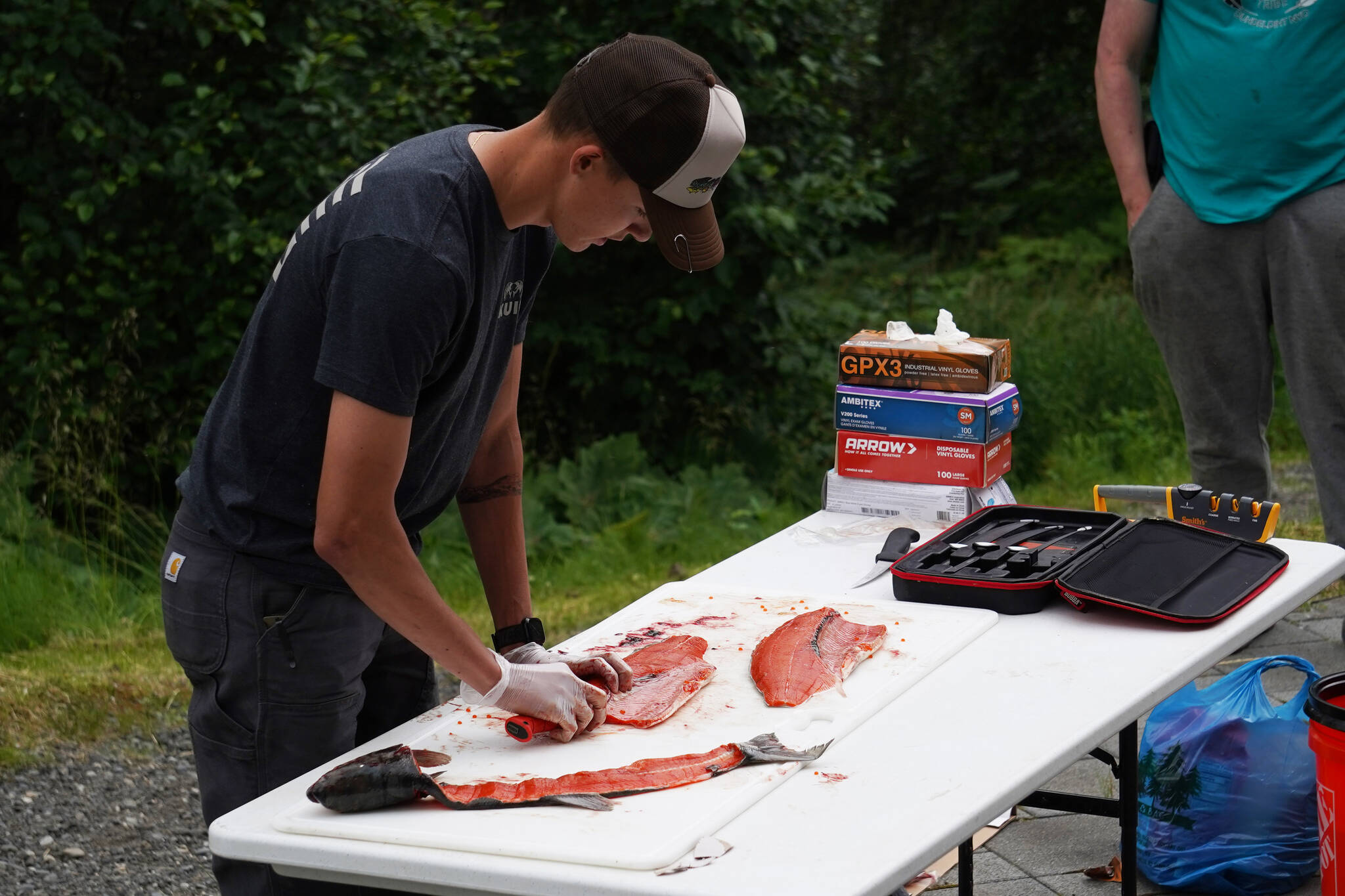 Ransom Hayes fillets a salmon during a smoked salmon demonstration, part of Fish Week 2023, on Wednesday, July 19, 2023, at the Kenai National Wildlife Refuge Visitor Center in Soldotna, Alaska. (Jake Dye/Peninsula Clarion)