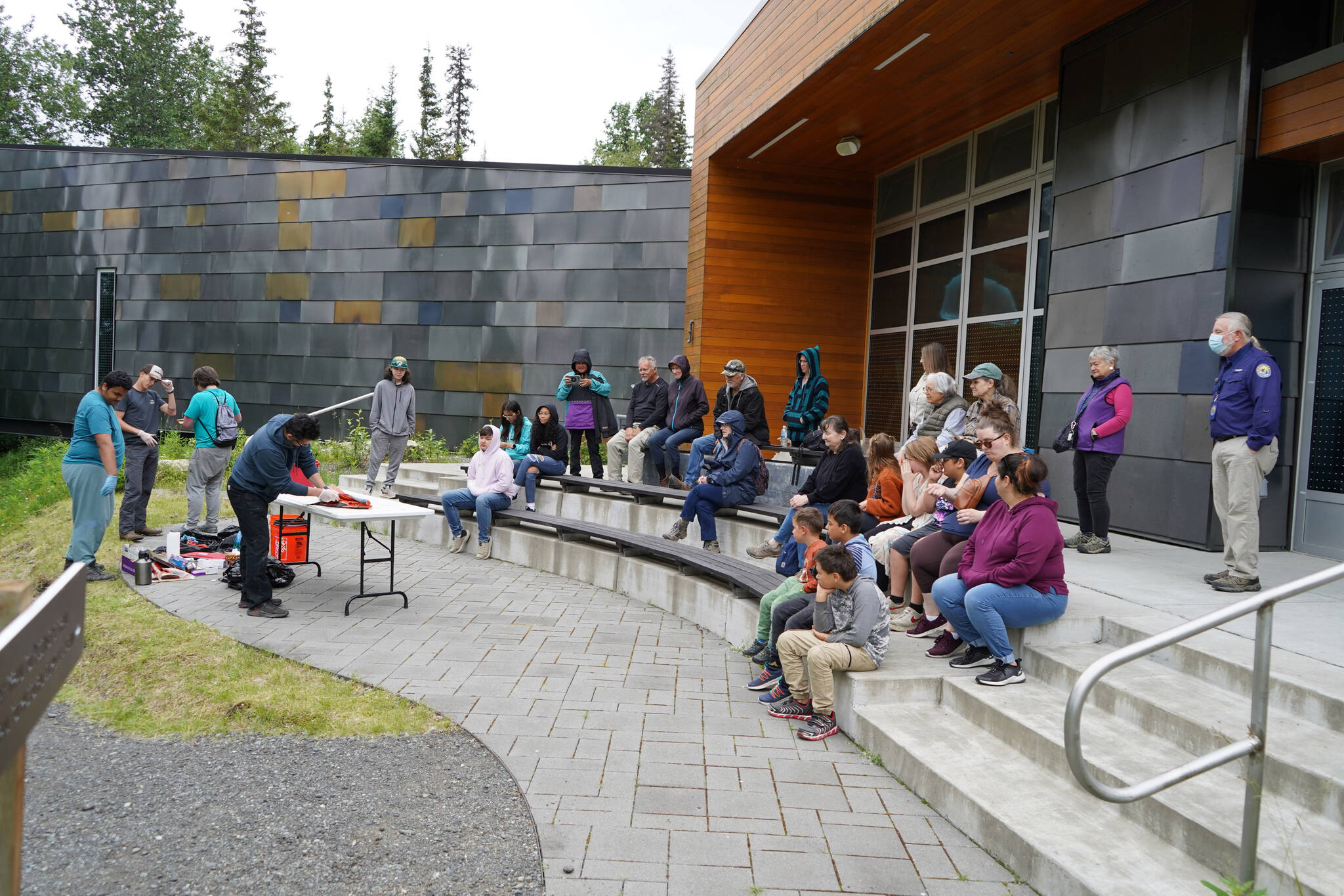 A crowd watches a smoked salmon demonstration, part of Fish Week 2023, on Wednesday, July 19, 2023, at the Kenai National Wildlife Refuge Visitor Center in Soldotna, Alaska. (Jake Dye/Peninsula Clarion)