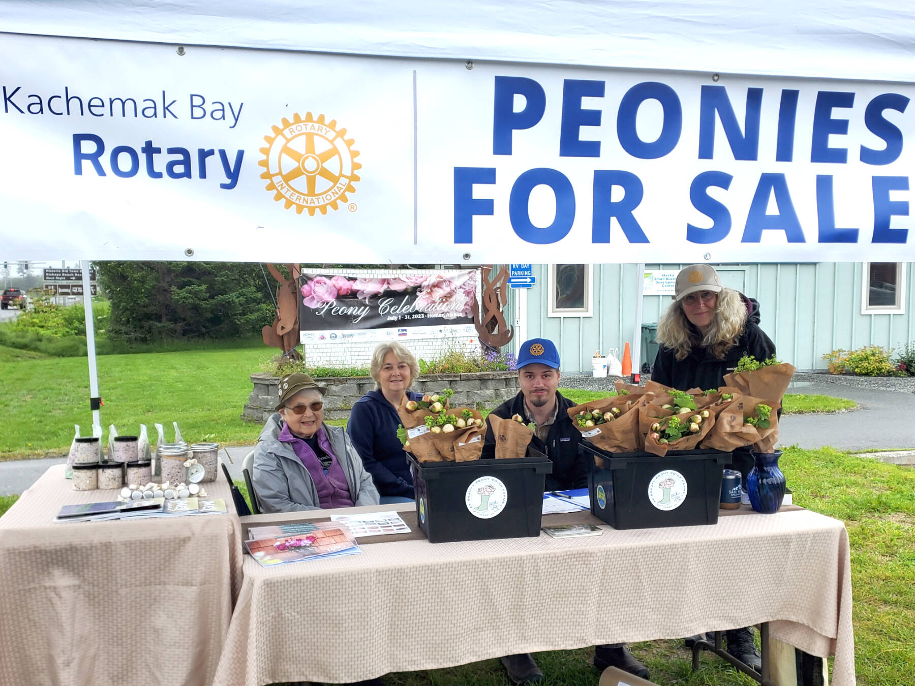 (from left to right) Homer-Kachemak Bay Rotary Club members Milli Martin, Linda Young, Owen Meyer and Laura Kelly, in partnership with the Alaska Beauty Peony Co-op, sell peonies in front of the Homer Chamber of Commerce and Visitor Center on Saturday, July 29, 2023 in Homer, Alaska. (Delcenia Cosman/Homer News)