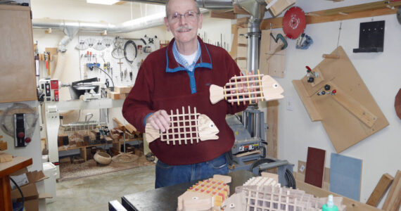 Homer woodworker Ted Heuer in photographed in his shop with rockfish and halibut trivets in 2022. Photo by Beth Heuer