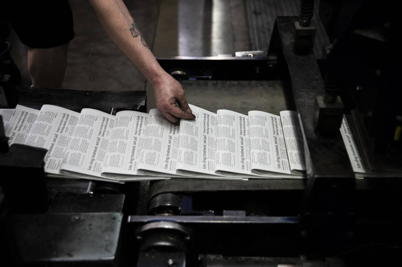 A press operator grabs a Herald newspaper to check over as the papers roll off the press in March 2022 in Everett. (Olivia Vanni / The Herald file photo)