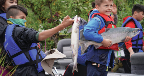 John “Gus” Knox, right, holds a salmon he caught during the Kenai River Junior Classic in Soldotna, Alaska, on Wednesday, Aug. 9, 2023. (Jake Dye/Peninsula Clarion)
