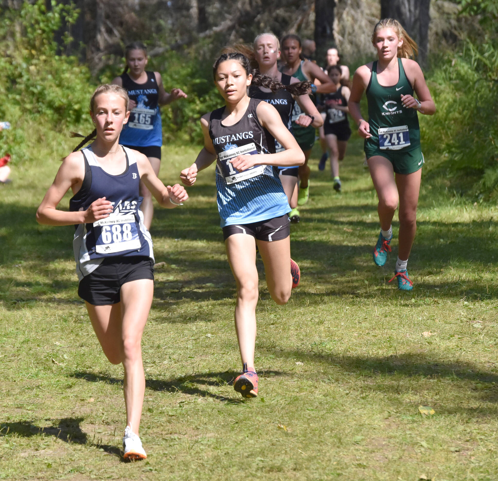 Soldotna’s Tania Boonstra leads a pack of runners down a hill at the midway point of the girls varsity race at the Ted McKenney XC Invitational on Saturday, Aug. 19, 2023, at Tsalteshi Trails just outside of Soldotna, Alaska. (Photo by Jeff Helminiak/Peninsula Clarion)