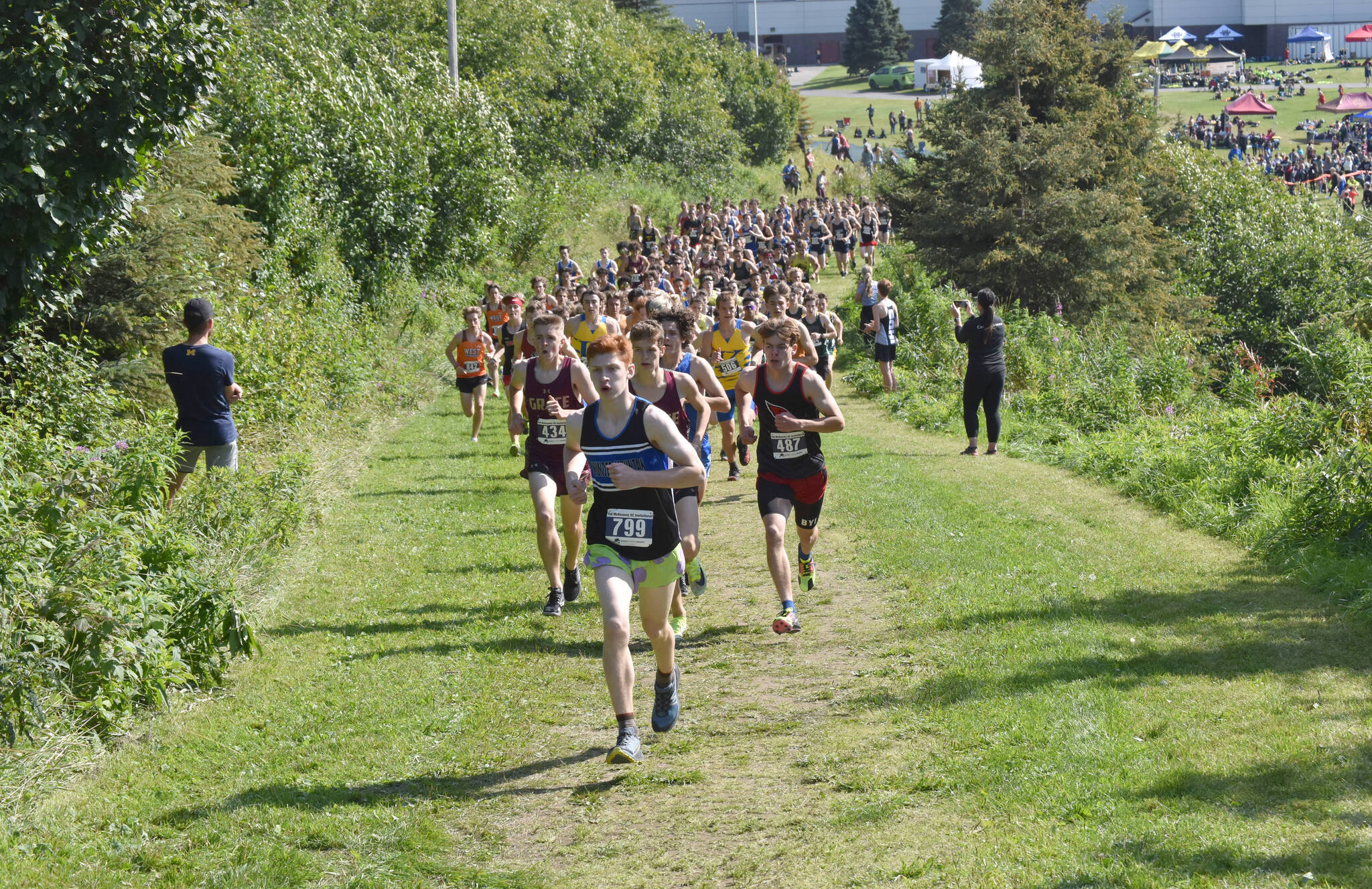 Erik Thompson of Juneau-Douglas: Yadaa.at Kale leads the pack up a hill at the beginning of the boys varsity race at the Ted McKenney Invitational on Saturday, Aug. 19, 2023, at Tsalteshi Trails just outside of Soldotna, Alaska. (Photo by Jeff Helminiak/Peninsula Clarion)