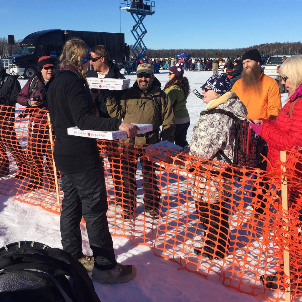 Rosco’s owner Ross Cameron (center) hands boxes of pizza over to Kristy Berington (front) at the Iditarod restart. Photo provided by Ross Cameron