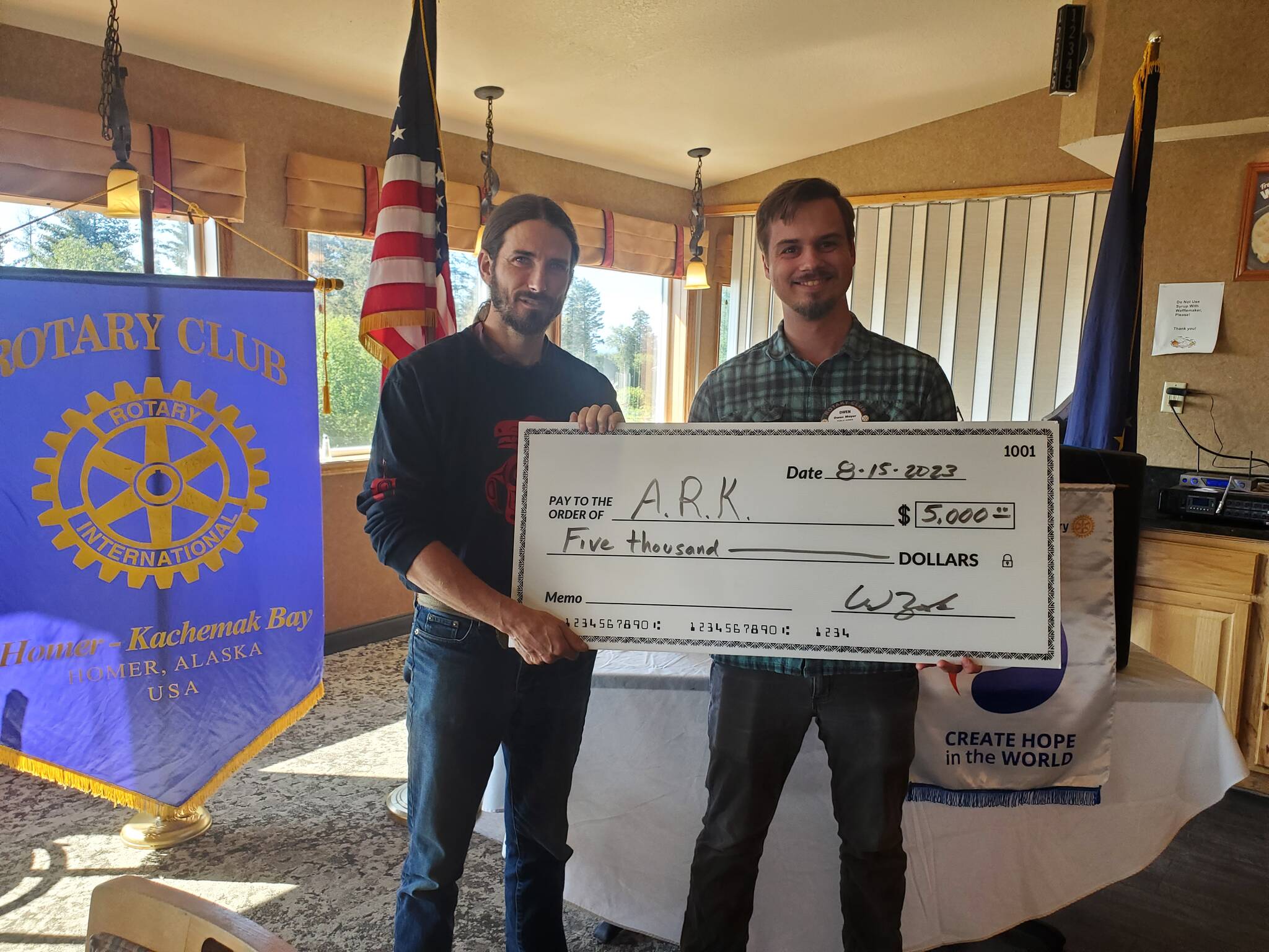 Homer-Kachemak Rotary Club president Owen Meyer (right) presents a donation check to Altruist Relief Kitchen founder Lucas Wilcox (left) on Tuesday, Aug. 15, 2023 in Homer, Alaska. Photo provided by Kim Zook