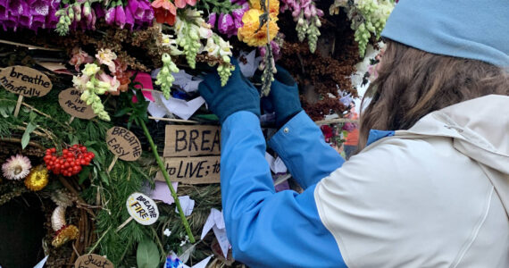 A community member places a message on the 2022 Burning Basket, “Breathe,” in Homer, Alaska. Photo by Christina Whiting