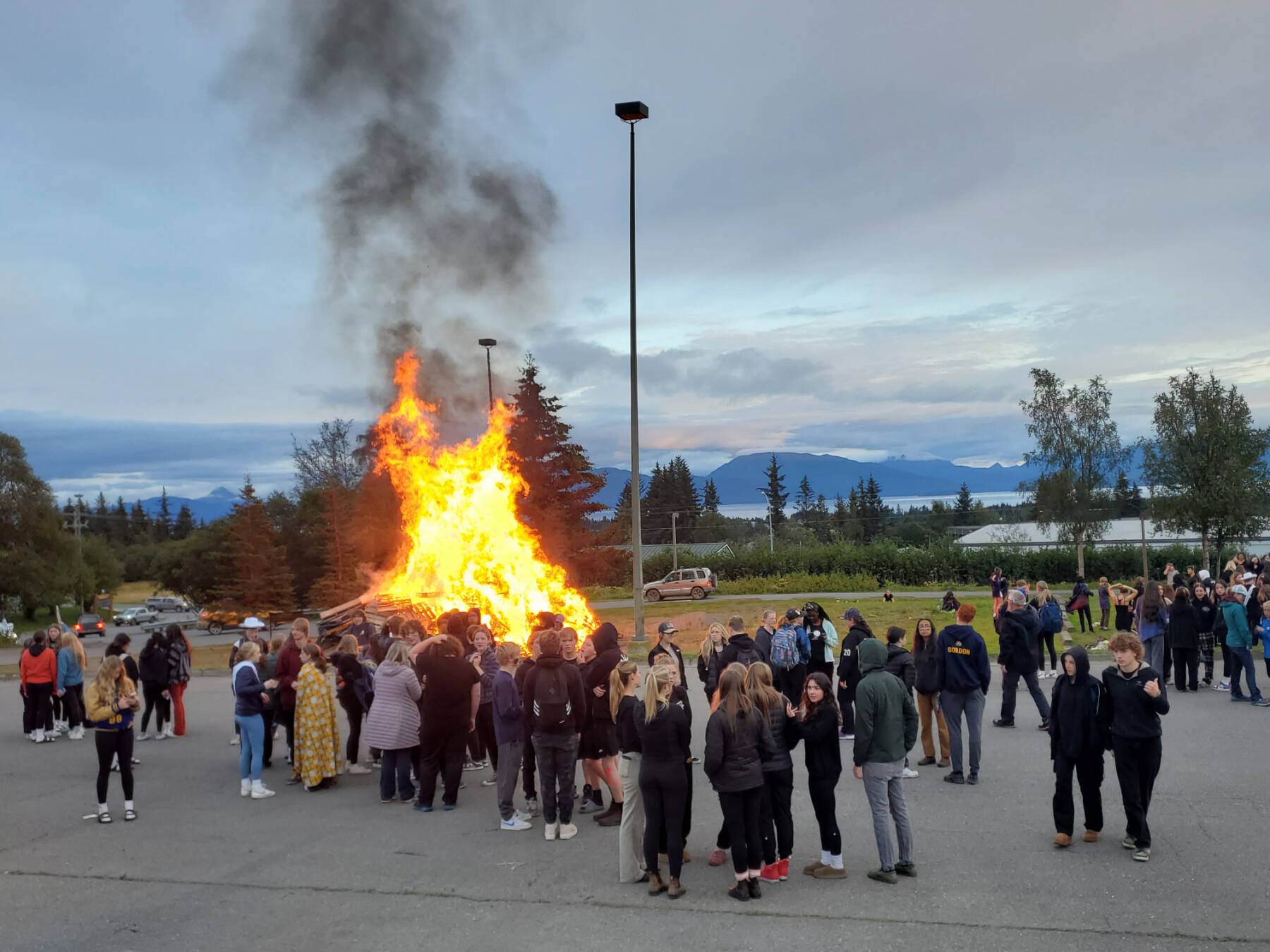 Students and community members gather around a bonfire in the Homer High School parking lot after the homecoming football game on Friday, Sept. 8, 2023 in Homer, Alaska. (Delcenia Cosman/Homer News)