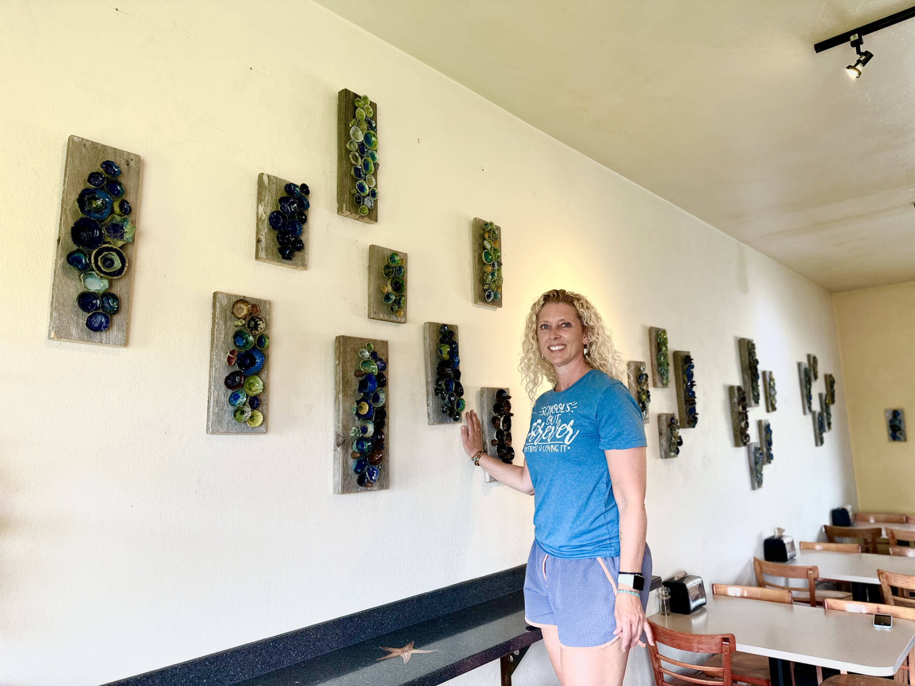 Artist Krista Etzwiler hangs her ceramic pinch pots on reclaimed wood at The Bagel Shop on East End Road in August in Homer, Alaska. (Photo provided by Krista Etzwiler)