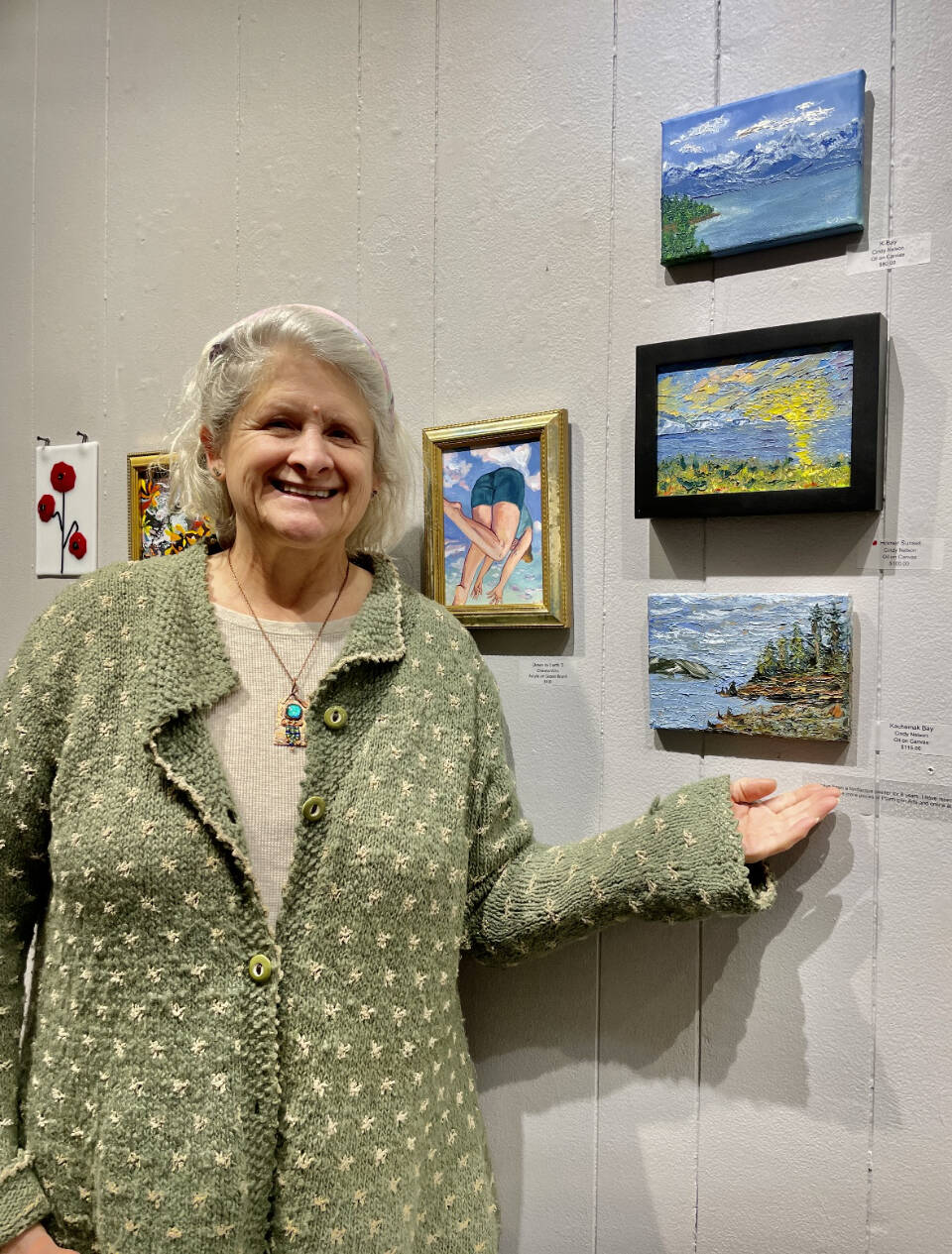 Artist Cindy Nelson poses with her three oil paintings on display in Homer Council on the Arts’ current “Fun with 5x7” exhibit on Thursday, Nov. 9, 2023 in Homer, Alaska. Photo provided by Cindy Nelson