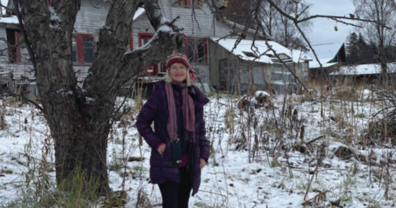 Homer musician Sunrise Sjoberg stands in front of the home she was born in near Thurston Drive on East End Road in Homer . Sunrise is the November featured musician at Bunnell’s Arts by Air program. (Emilie Springer/Homer News)