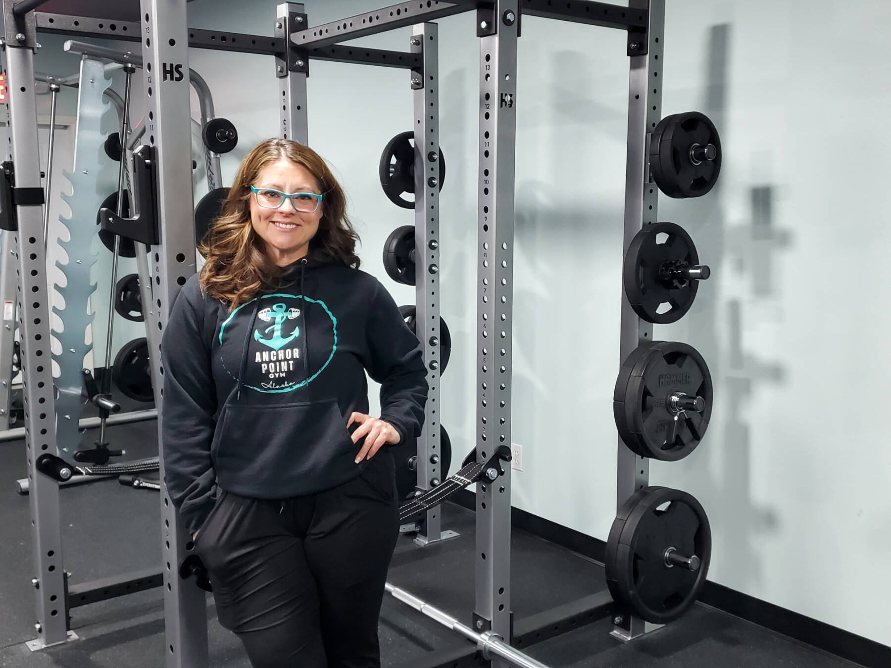 Anchor Point gym owner Heidi Cox is photographed by new weightlifting equipment during the gym’s grand opening on Friday, Nov. 10, 2023 in Anchor Point, Alaska. (Delcenia Cosman/Homer News)