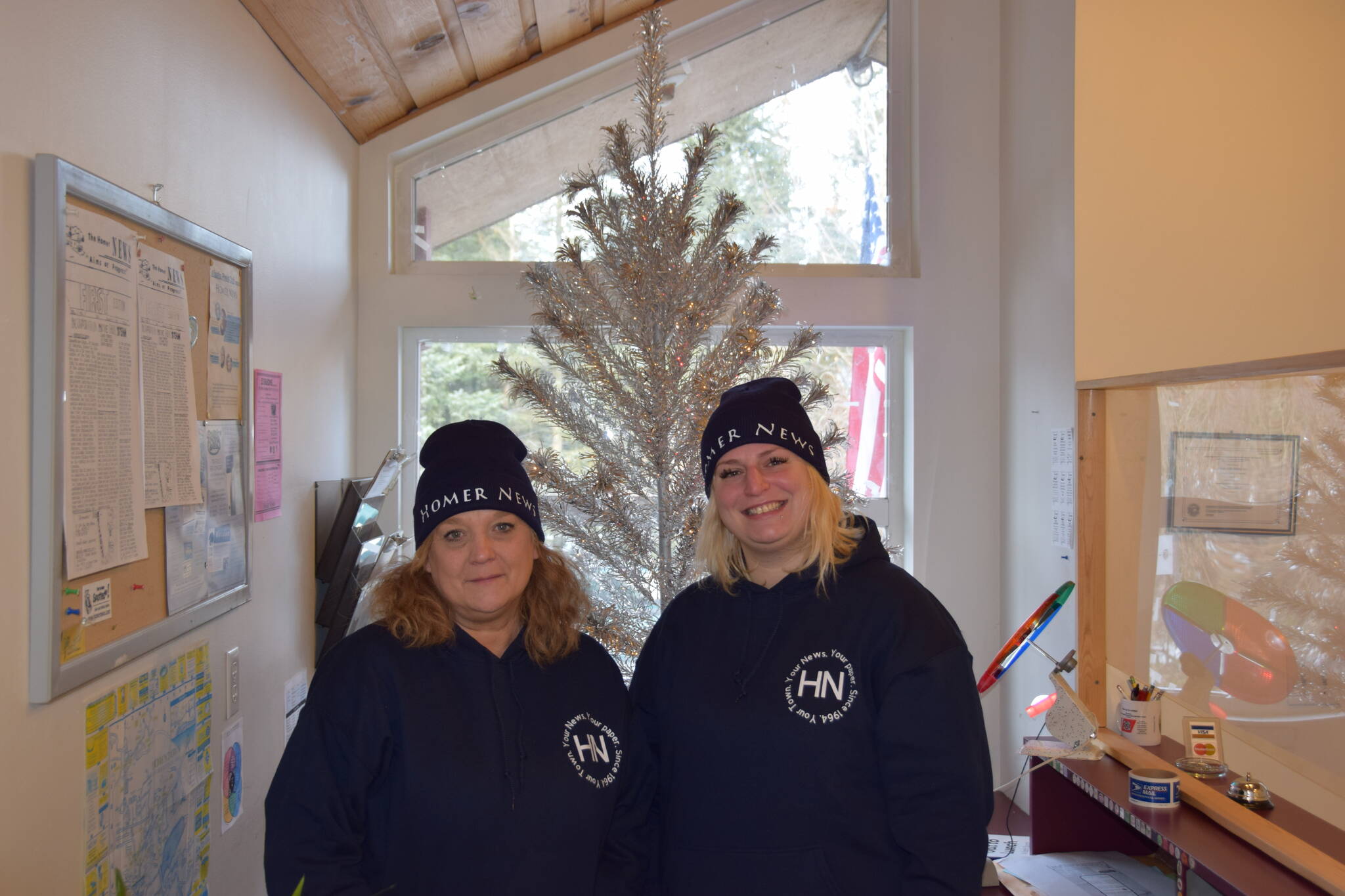 Homer News multimedia sales consultant Callie Steinberg and Peninsula Clarion regional sales manager Cara Hall pose in front of the office Christmas tree at the Homer News Office on Friday, Dec. 5, 2023.