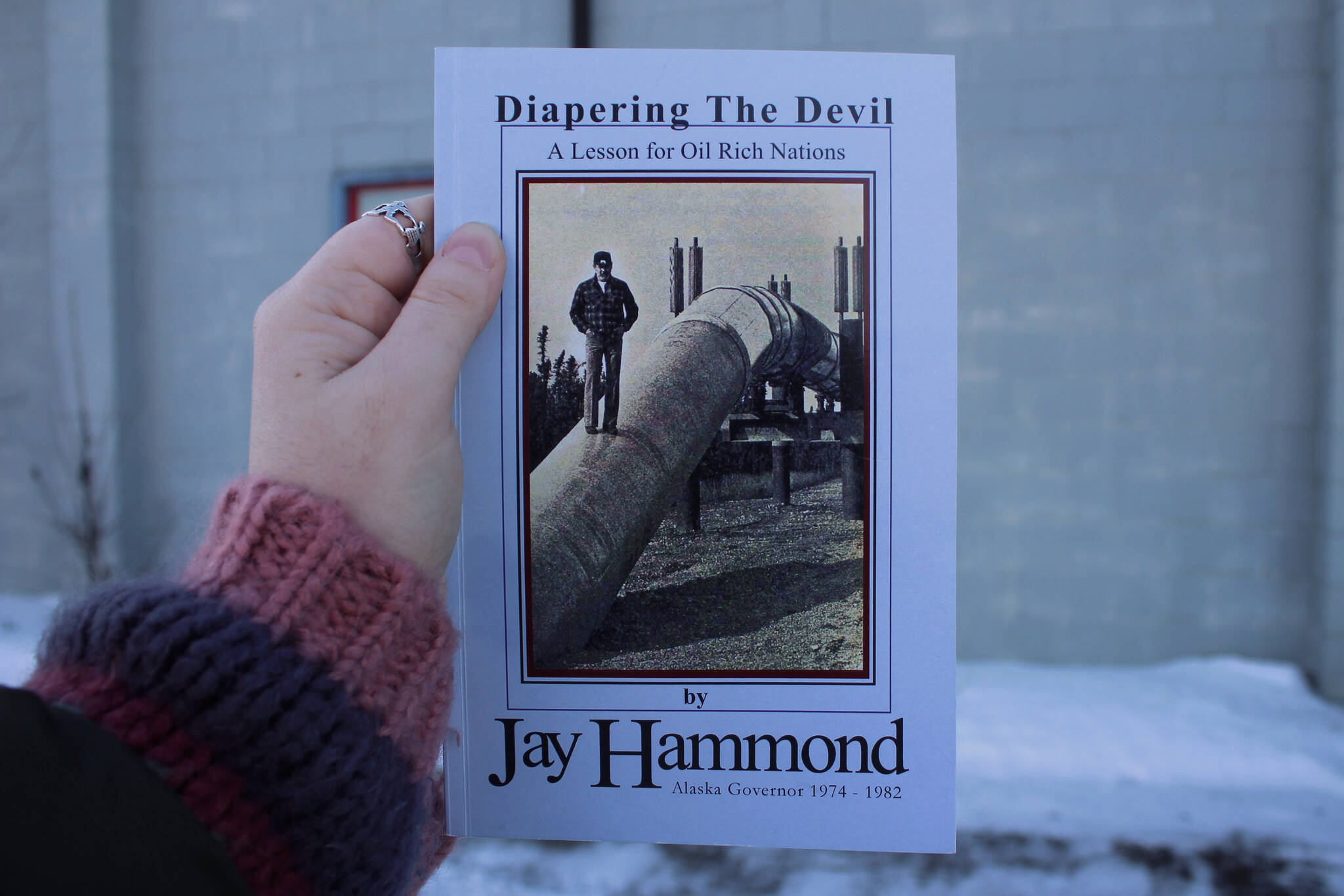 A copy of Jay Hammond's "Diapering The Devil: A Lesson for Oil Rich Nations" is held outside the Peninsula Clarion office on Tuesday, Jan. 9, 2024 in Kenai, Alaska. (Ashlyn O'Hara/Peninsula Clarion)