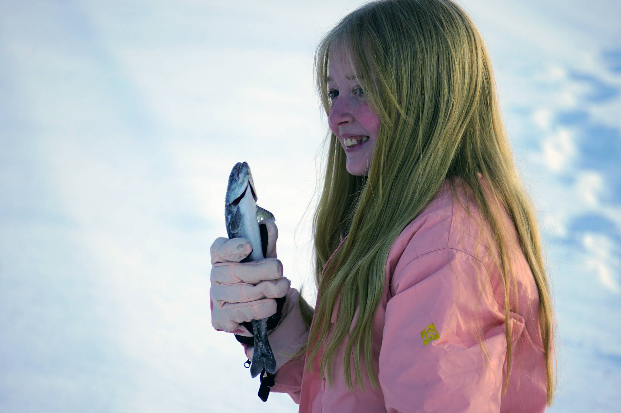 Natalie Kiech, a student of Soldotna Elementary, holds up a rainbow trout she caught during Salmon in the Classroom ice fishing at Sport Lake in Soldotna, Alaska, on Tuesday, Feb. 6, 2024. (Jake Dye/Peninsula Clarion)