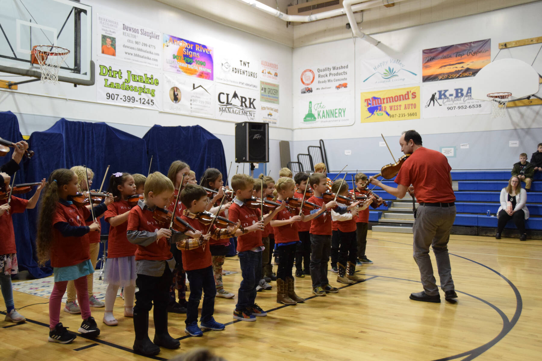 String Program Director Abimael Melendez (right) leads the Homer OPUS group in a series of songs on the violin at the Anchor Point Snow Rondi Cabin Fever Variety Show on Thursday, Feb. 29, 2024 at Chapman School in Anchor Point, Alaska. (Delcenia Cosman/Homer News)