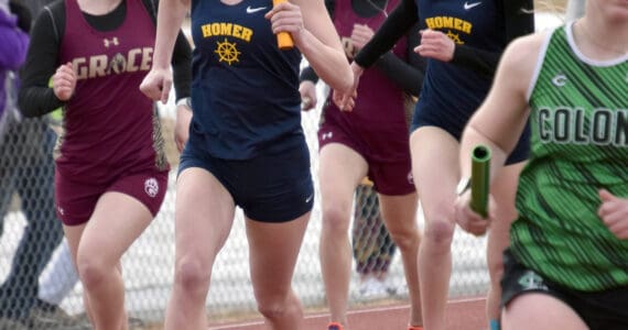 Homer’s Brightly Thoning hands to Gracie Miotke in the 1,600-meter relay Saturday, April 20, 2024, at the Soldotna Invitational at Soldotna High School in Soldotna, Alaska. (Photo by Jeff Helminiak/Peninsula Clarion)