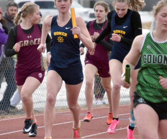 Homer’s Brightly Thoning hands to Gracie Miotke in the 1,600-meter relay Saturday, April 20, 2024, at the Soldotna Invitational at Soldotna High School in Soldotna, Alaska. (Photo by Jeff Helminiak/Peninsula Clarion)
